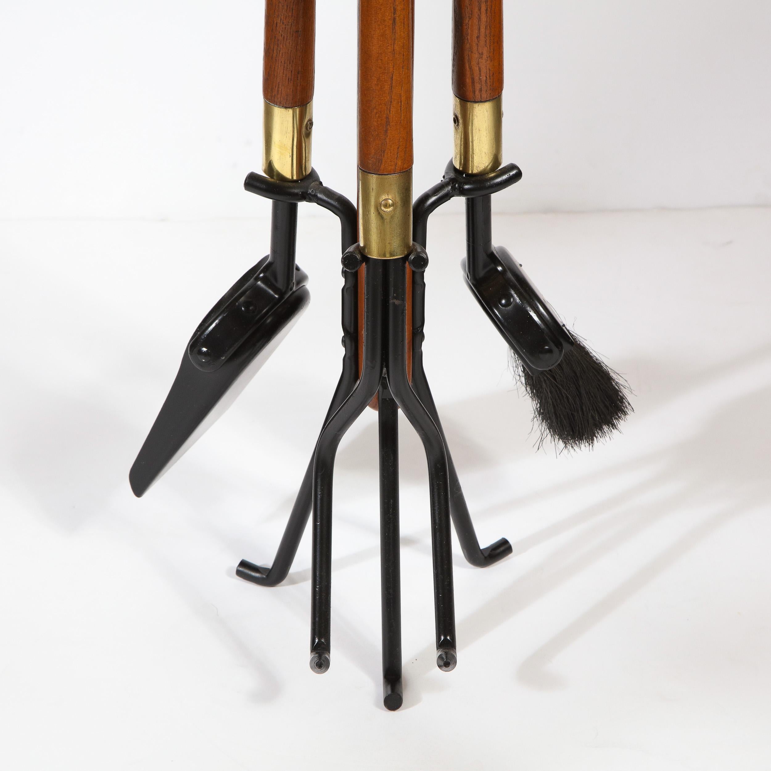 This refined Mid-Century Modern four piece fire tool set was realized in the United States, circa 1960. It features a poker, brush and shovel with hand rubbed walnut handles offering rounded subtly protuberant ends, and black enamel bottoms with