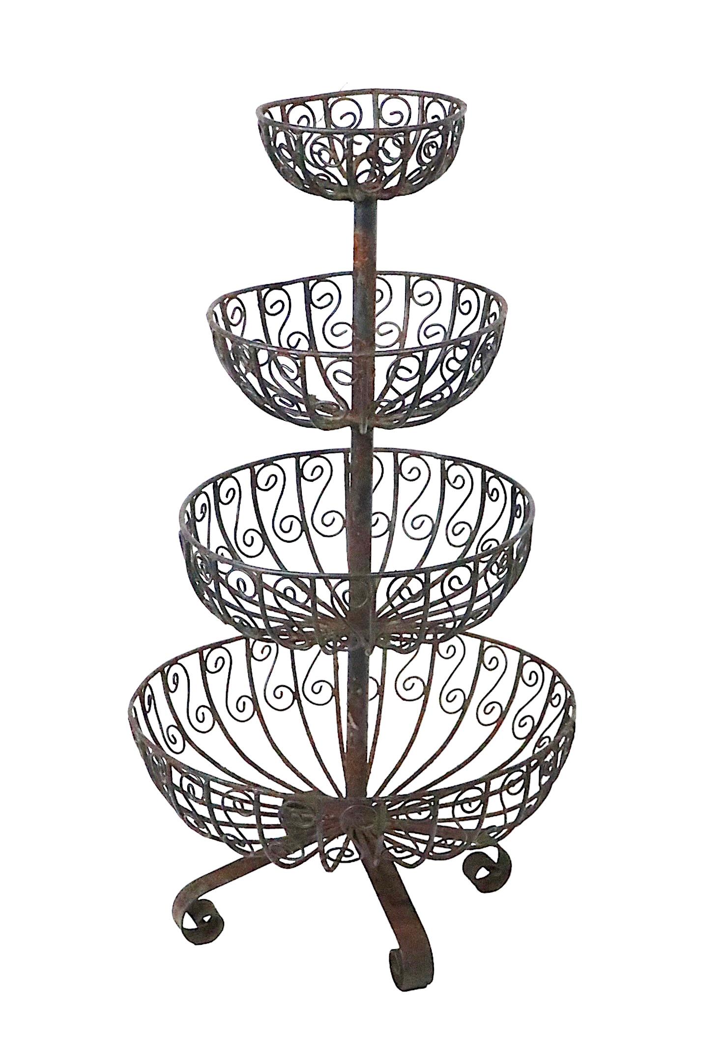 Charming wrought iron planter having four basins each of graduated size in defending order, mounted on the vertical standard, with a four foot curlicue form base. This nice decorative stand is structurally sound and sturdy, it looks like it probably