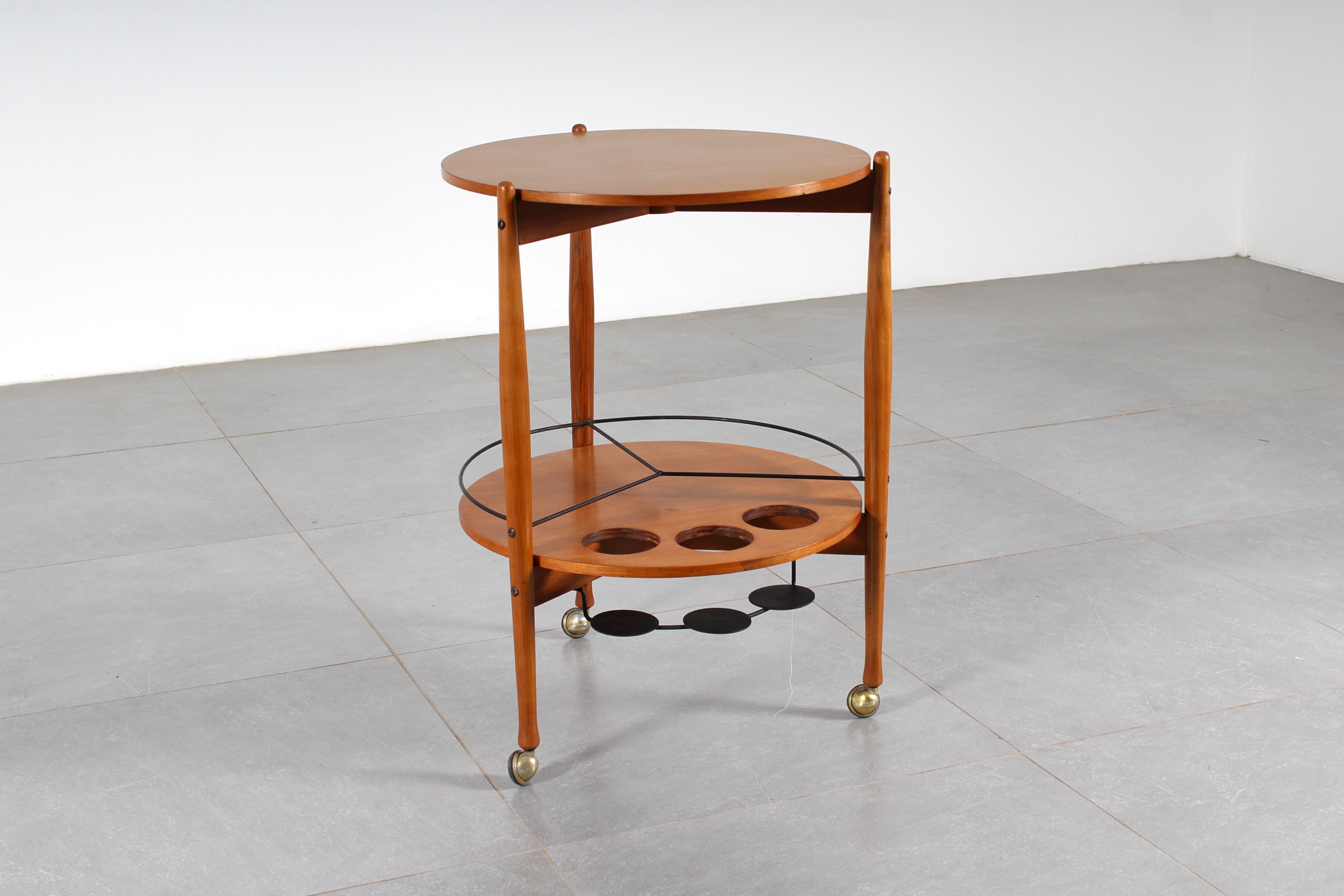 Sehr eleganter Barwagen aus Holz, mit doppelter Ablage und schwarz lackiertem Metallflaschenhalter. Hergestellt in Italien von Fratelli Reguitti, mit Heißprägung auf der Unterseite, aus den 60er Jahren.
Alters- und gebrauchsbedingte