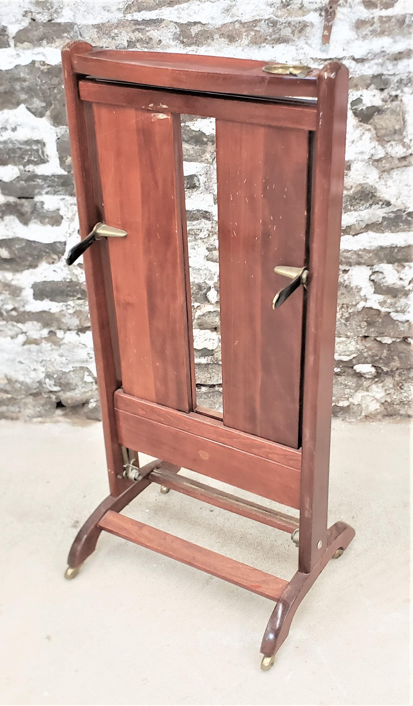 This Mid-Century Modern era wooden men's valet stand was designed by Fratelli Reguitti of Italy in approximately 1960 in the period Mid-Century style. This valet is done in solid wood with a vide poche tray at the top, complete with an inserted