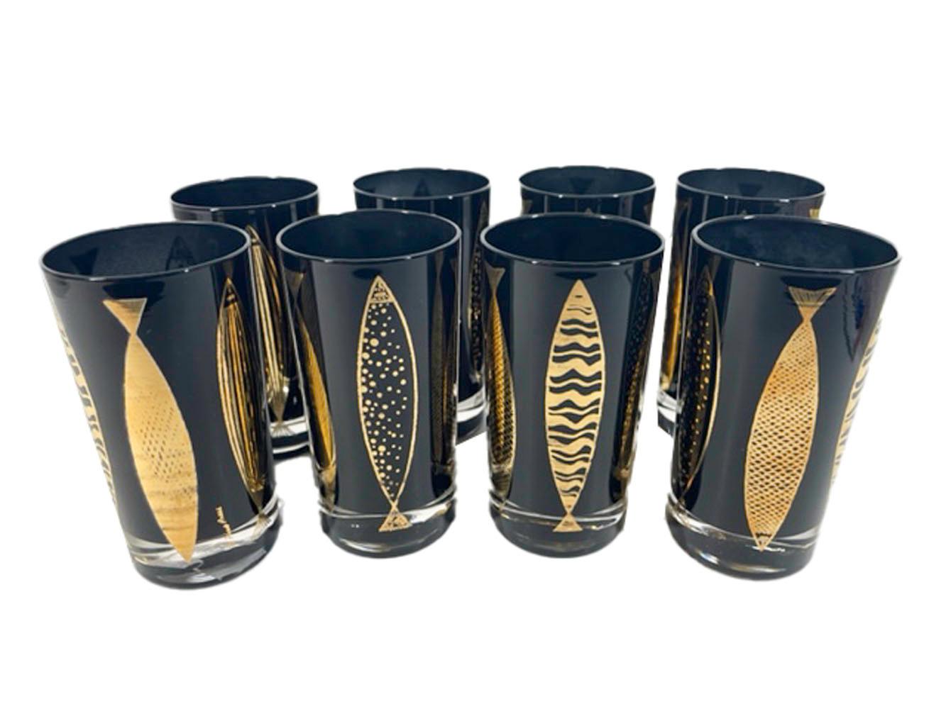 Set of 8 Fred Press highball glasses of clear glass with black frosted interiors and 22 karat gold stylized vertical fish in the atomic style on the exterior.