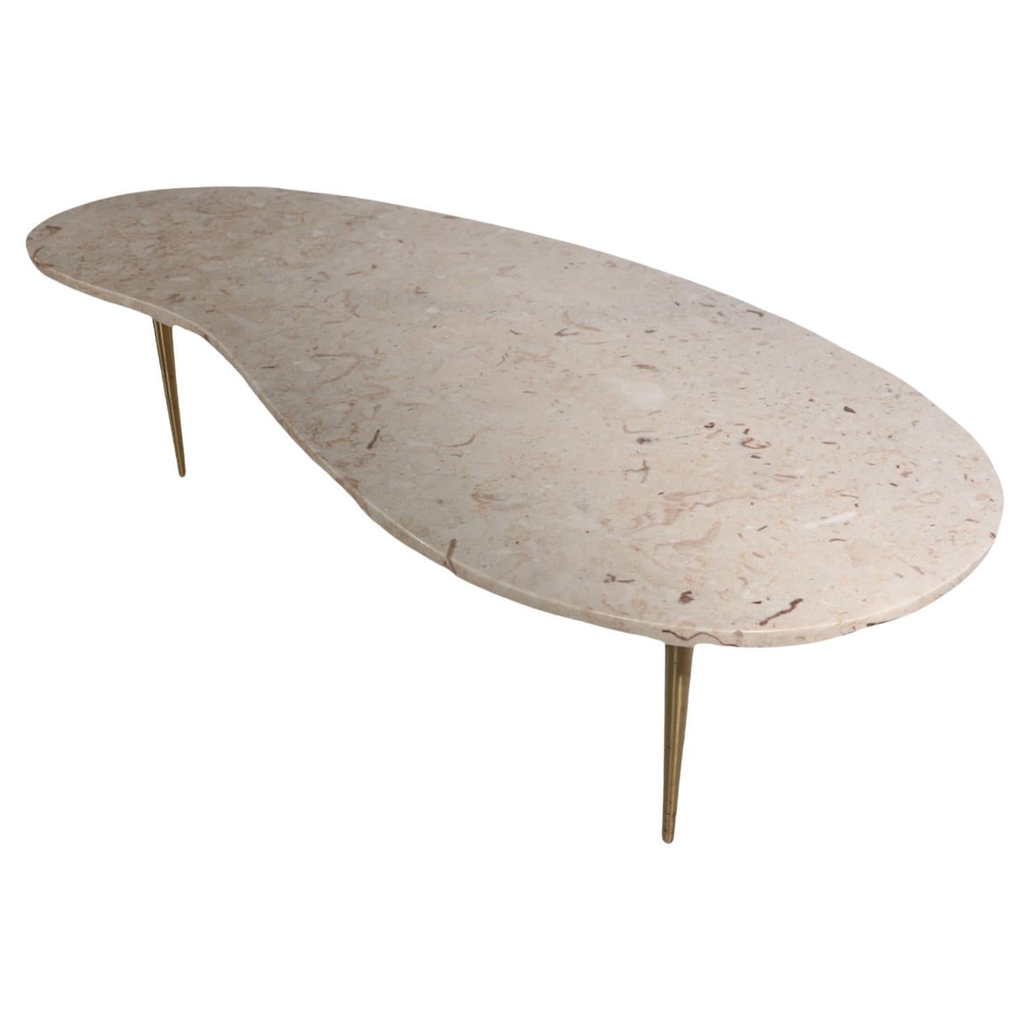 Voguish modern marble top coffee, cocktail table having a thick ( 1 in. ) kidney shaped top, which rests of splayed tapered pole brass legs. The marble has an inconsequential chip at the bottom edge, please see images. 
The marble is marked made in