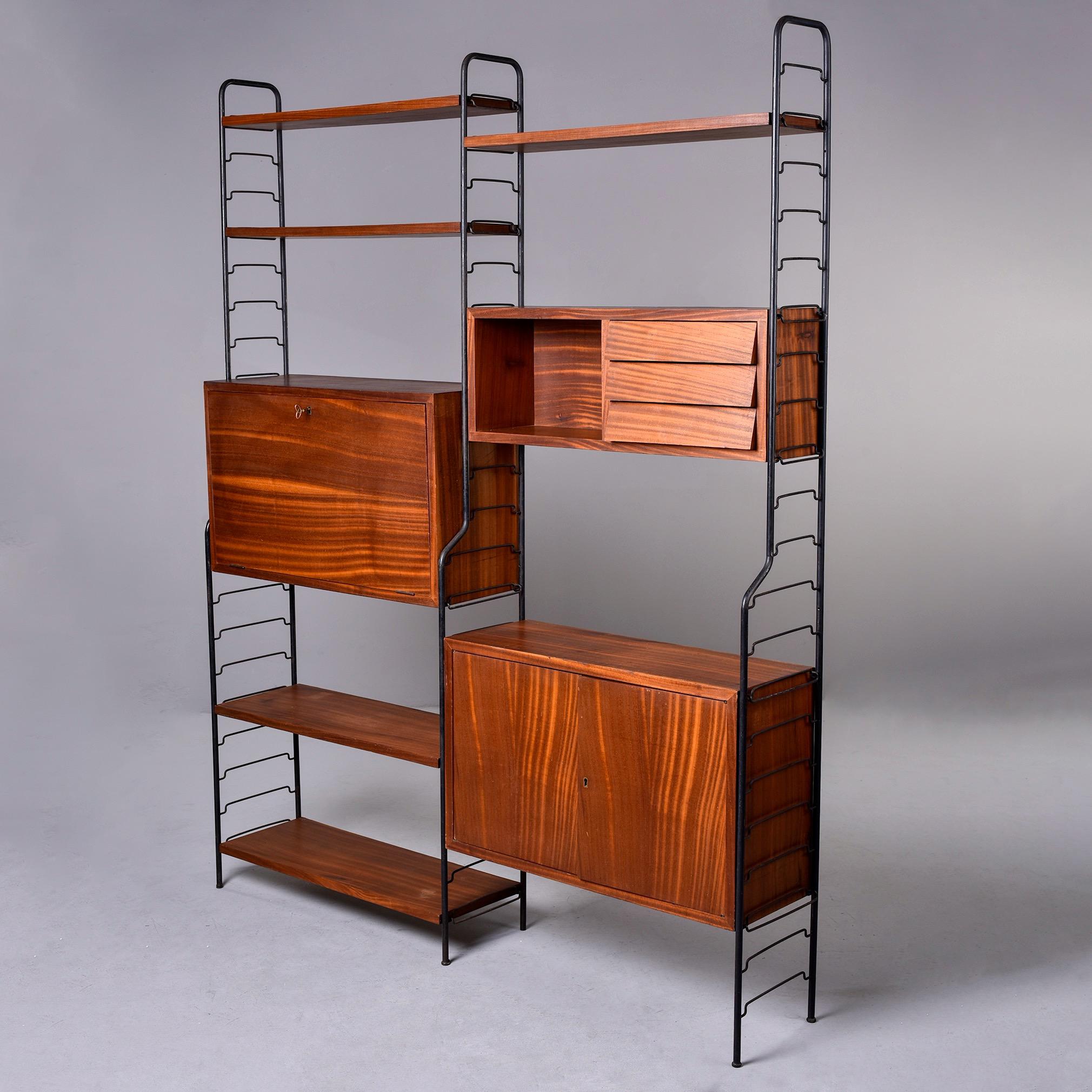 Found in Italy, this circa 1960s free standing modular shelf unit consists of three black metal frame sections five shelves, a locking cabinet with fold down desk, a cabinet with an open shelf and three drawers and a locking two door cabinet. The
