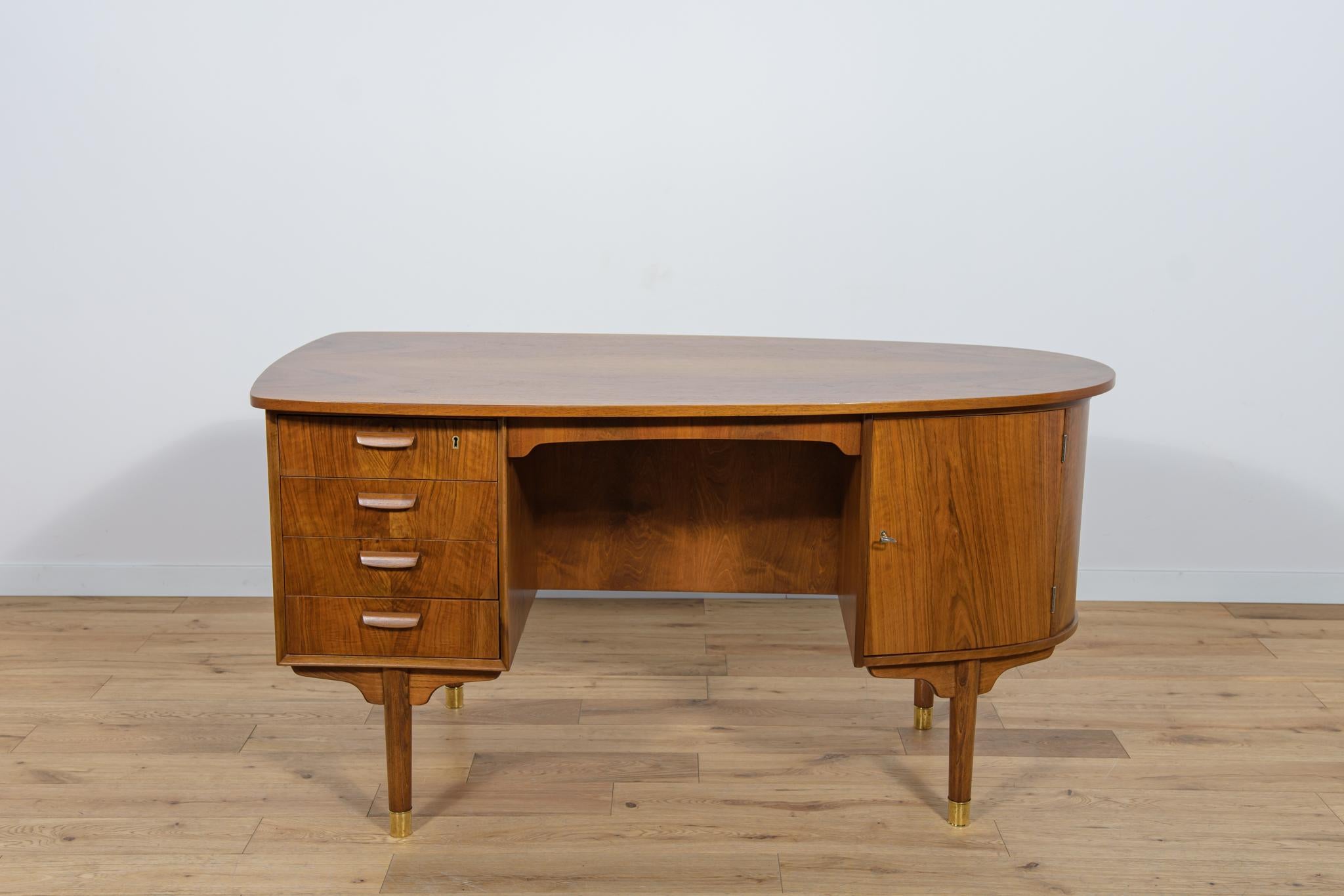 Freestanding desk made in Denmark in the 1960s in Mid Century style. It is made of walnut wood with profiled handles. The furniture has a unique rounded shape, giving it a unique character. It consists of two modules, on the left there are four