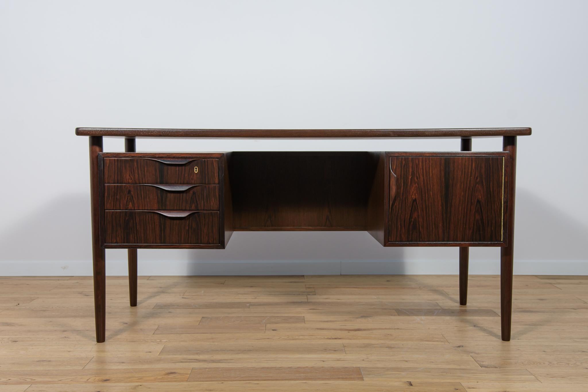 The free-standing desk manufactured in Denmark in the 1960s. The furniture is made of rosewood and has profiled handles. The free-standing desk consists of two modules, on the left side there are three drawers, and on the right side there is a