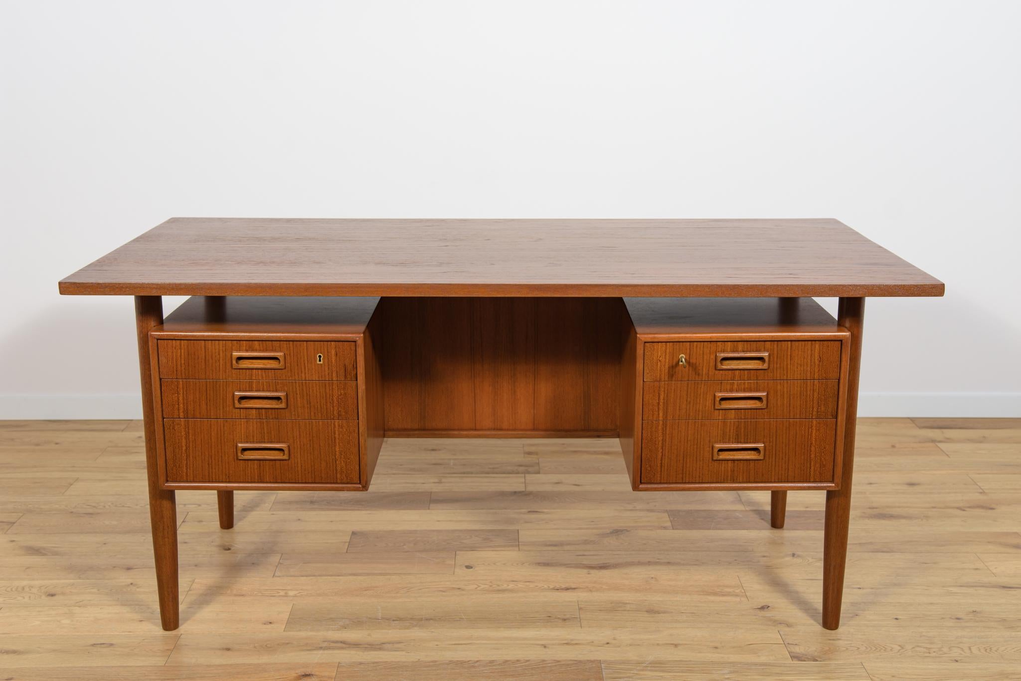 A desk designed by Danish designer Arne Vodder in the 1960s. The desk is made of teak wood and is free-standing thanks to the finished back with an open storage space. On the front there are two drawer modules with three drawers (two lockable). The