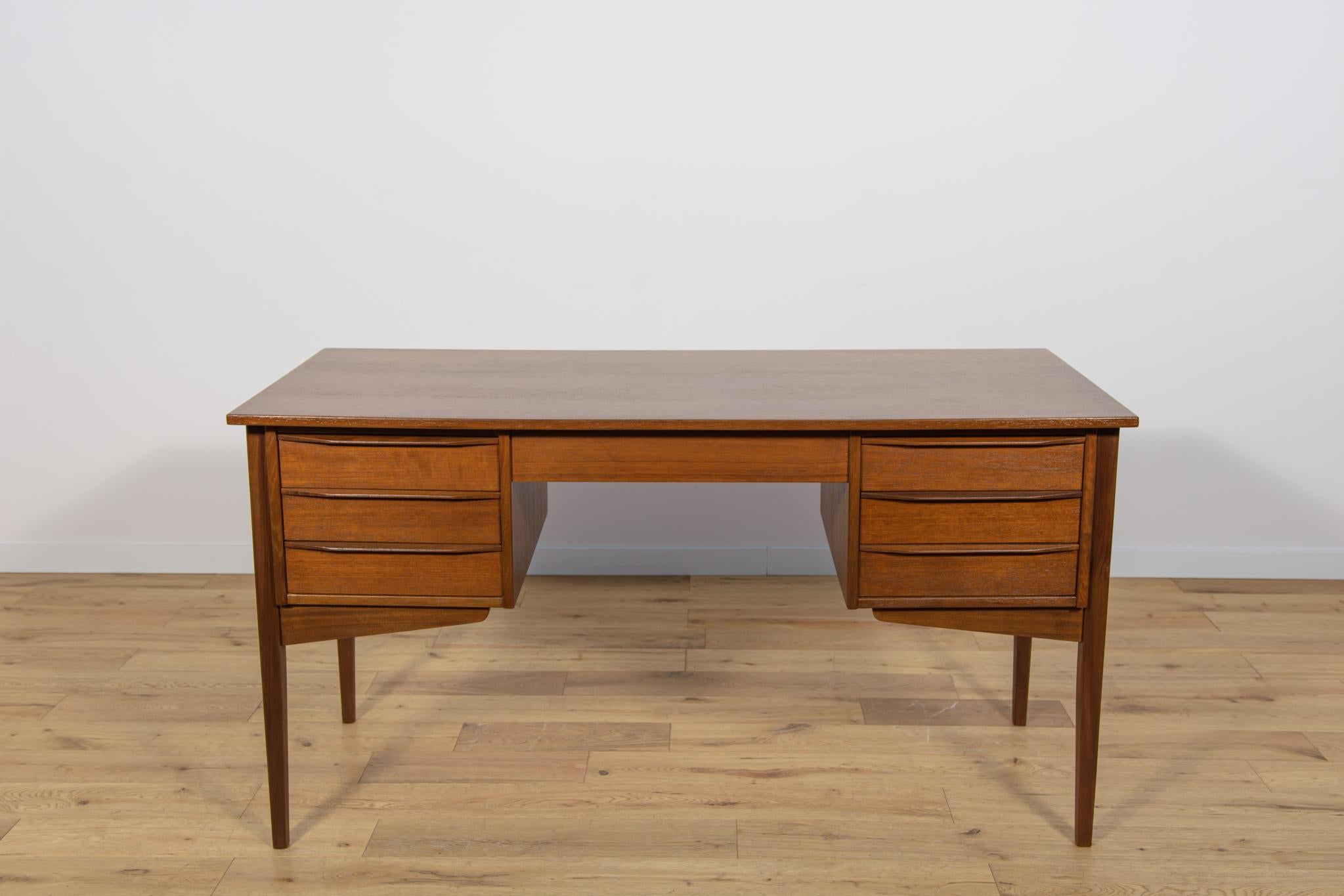 Questa scrivania è stata realizzata in Danimarca negli anni Sessanta. È realizzato in legno di teak con manici profilati. È composto da due moduli, a sinistra e a destra ci sono tre cassetti.  Gli elementi in teak sono stati puliti con la vecchia