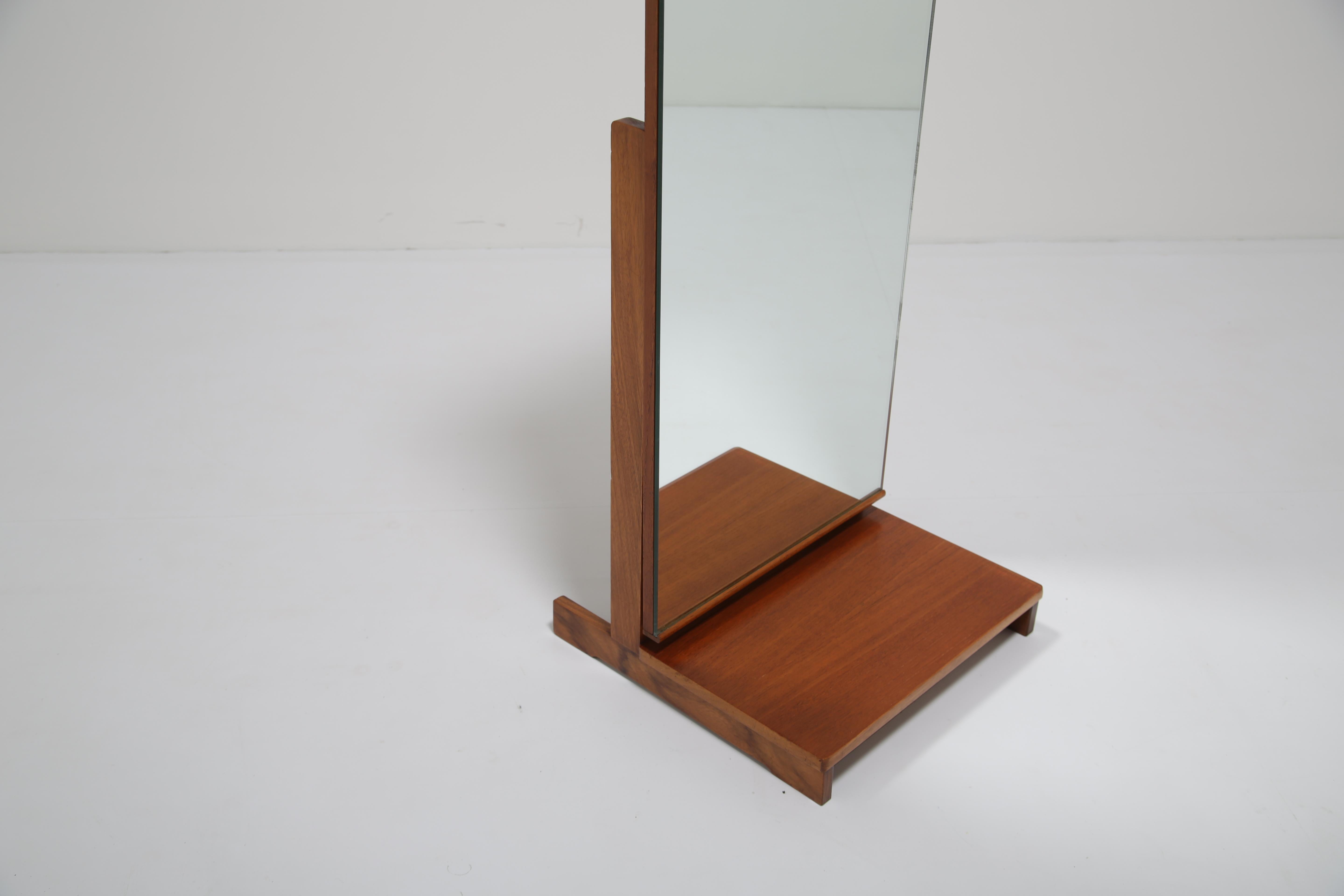 Miroir chevaleresque autoportant en teck, magnifiquement proportionné, fabriqué en Grande-Bretagne dans les années 1960. Cette pièce reflète la sophistication discrète du design du milieu du siècle, où les lignes épurées et les détails fonctionnels