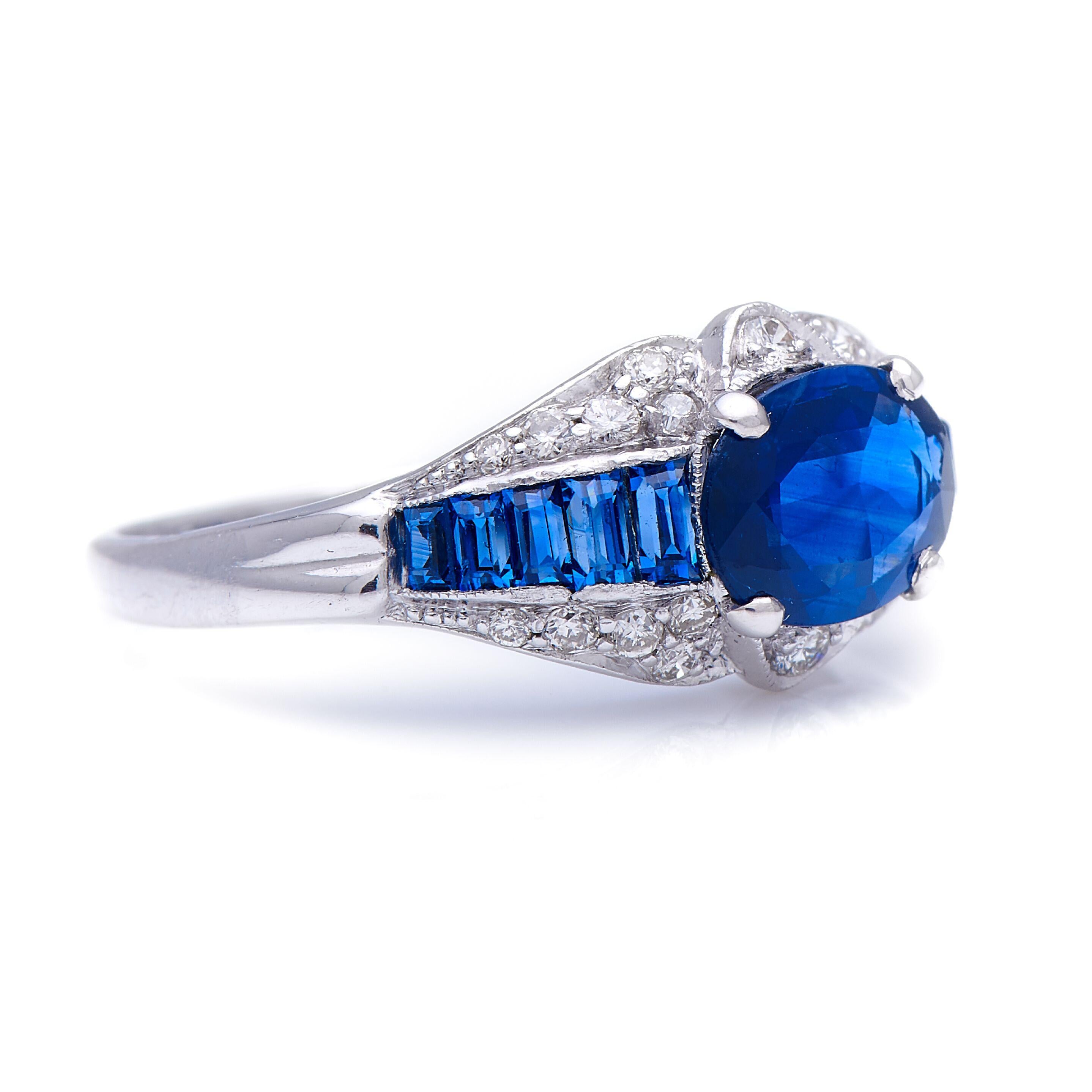 Sapphire and diamond ring, 20thcentury. The clever setting of this ring takes a central oval sapphire and several smaller calibré-cut sapphires and seamlessly fuses them together into a continuous band of blue. The millgrained diamond-set edges
