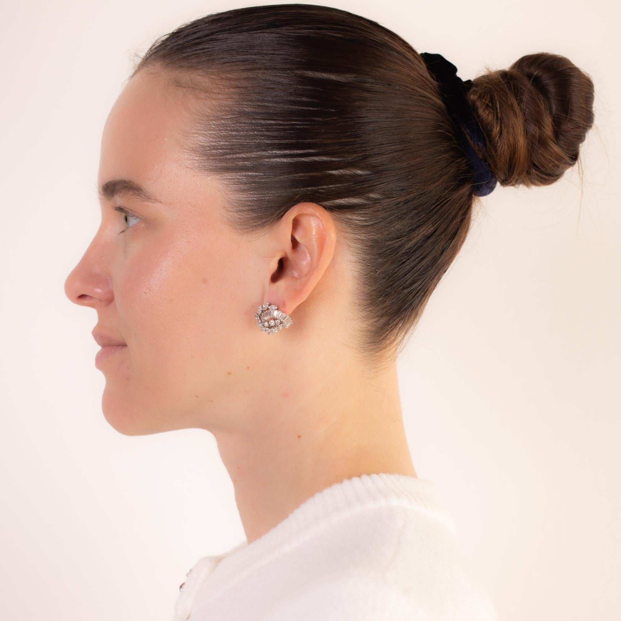 Ces boucles d'oreilles exquises en platine français du milieu du siècle éblouissent avec 18 diamants marquise, 28 diamants baguette et 6 diamants ronds de taille brillant, totalisant environ 4,70 carats, couleur D-E, pureté VS. Un design intemporel