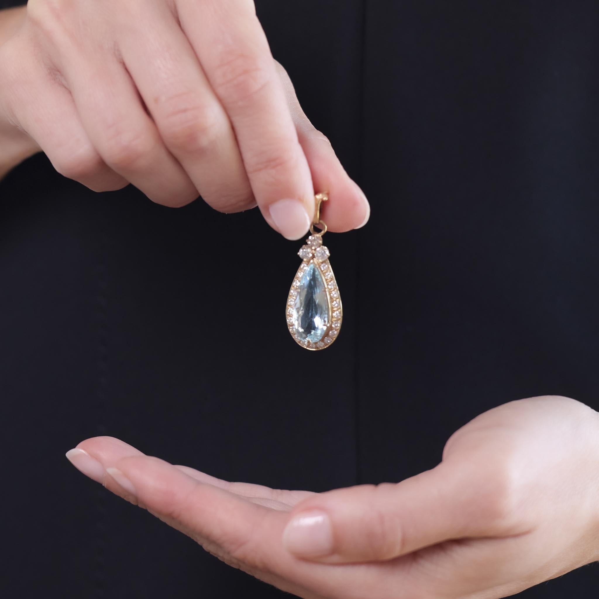 This Mid Century pendant from the 1950s is crafted in 18k yellow gold and features a pear cut aquamarine weighing approximately 6.40 carats. It is accented by 24 round brilliant, old European, and old mine cut diamonds totaling approximately 1.30