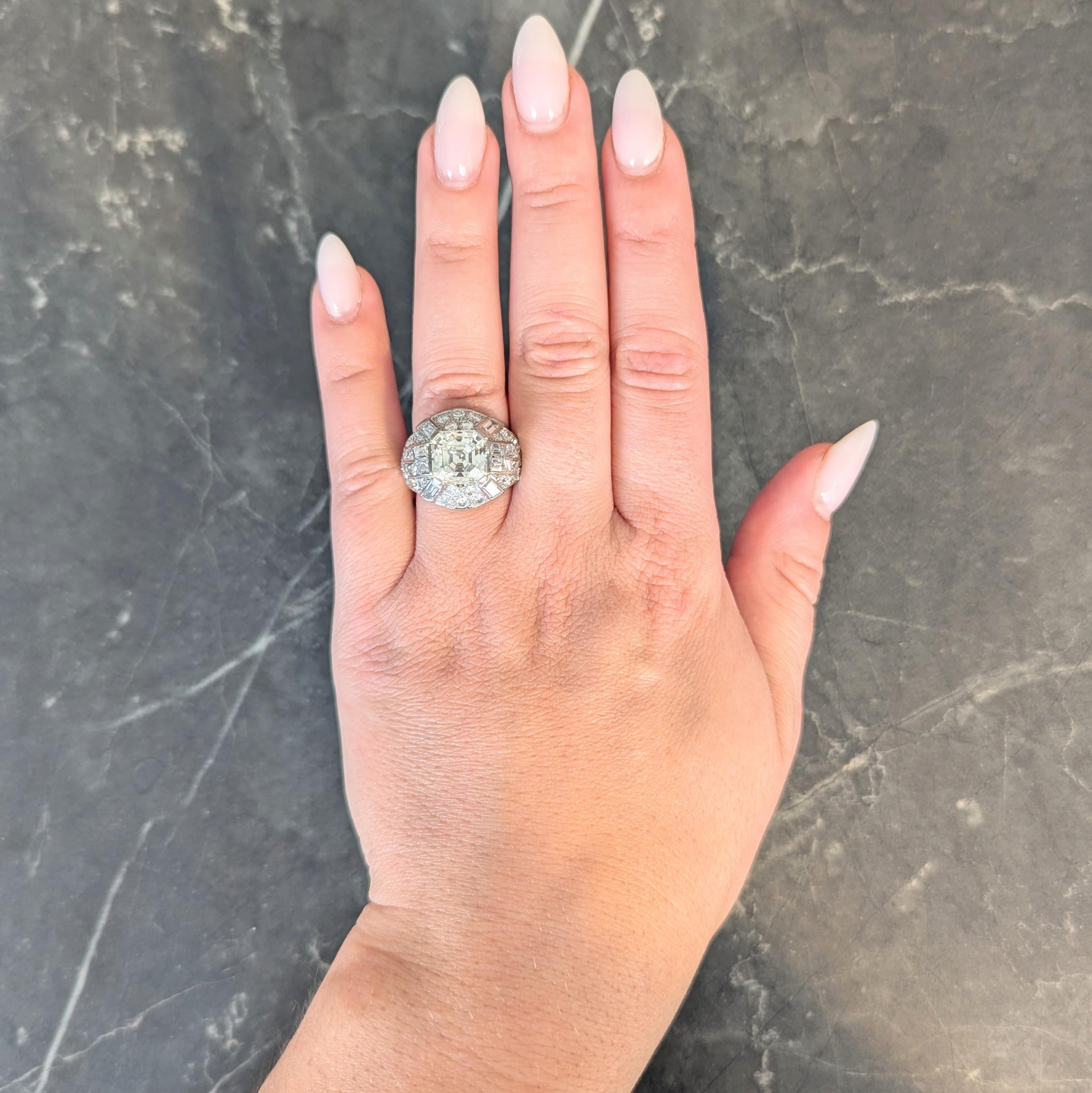 Anello a forma di cupola con al centro un diamante taglio Asscher di 4,49 carati.
Colore M con purezza VVs1 - incastonato con linguette larghe in un motivo geometrico.
Accentuato da stazioni di diamanti a taglio trapezoidale incastonati a filo sulle