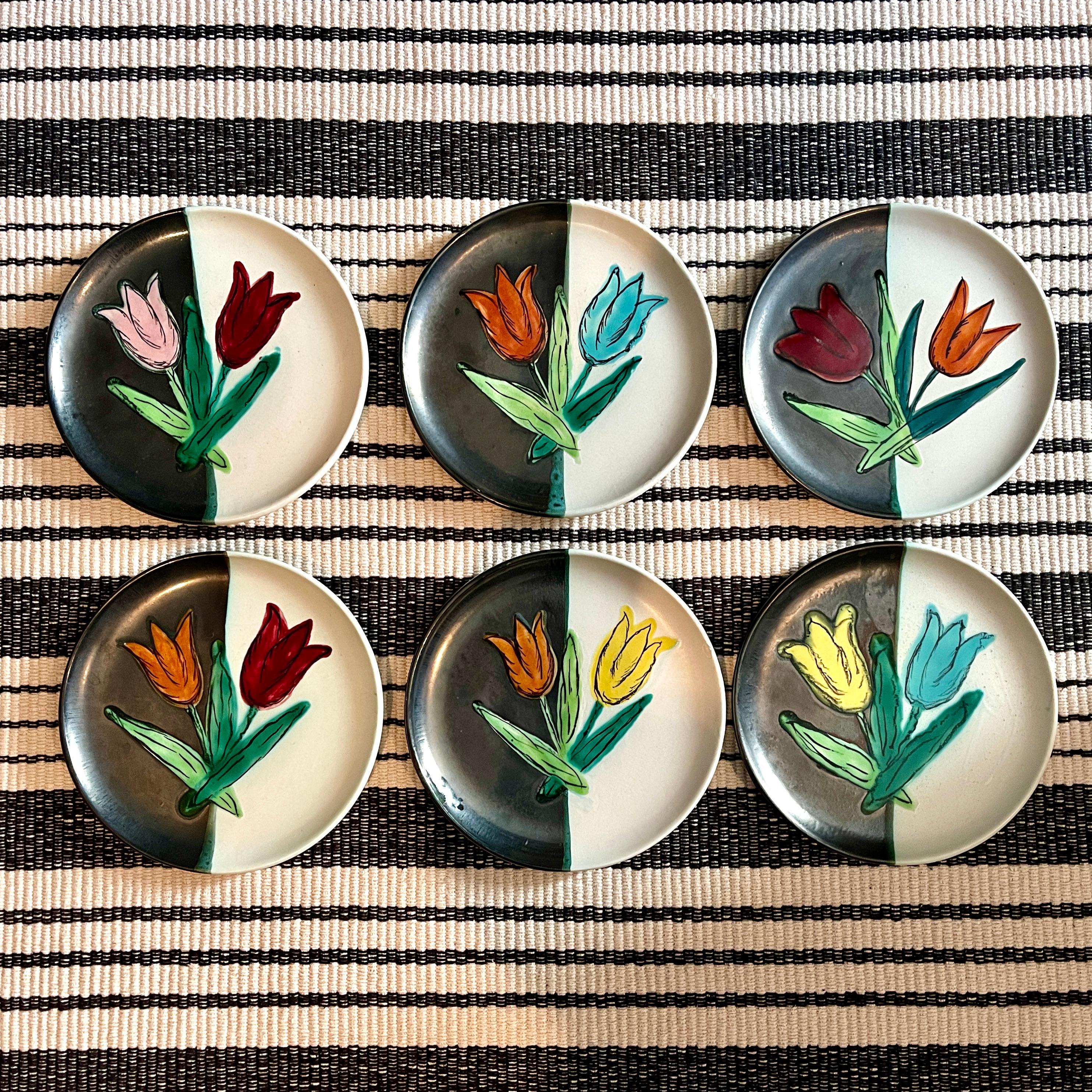 From the Atelier Cérenne à Vallauris in France, a set of six pottery Tulip plates, circa 1940-1950.

Each plate is finished in a matte glazing of half black and half white, with a pair of raised, glossy glazed tulips painted in complimentary color