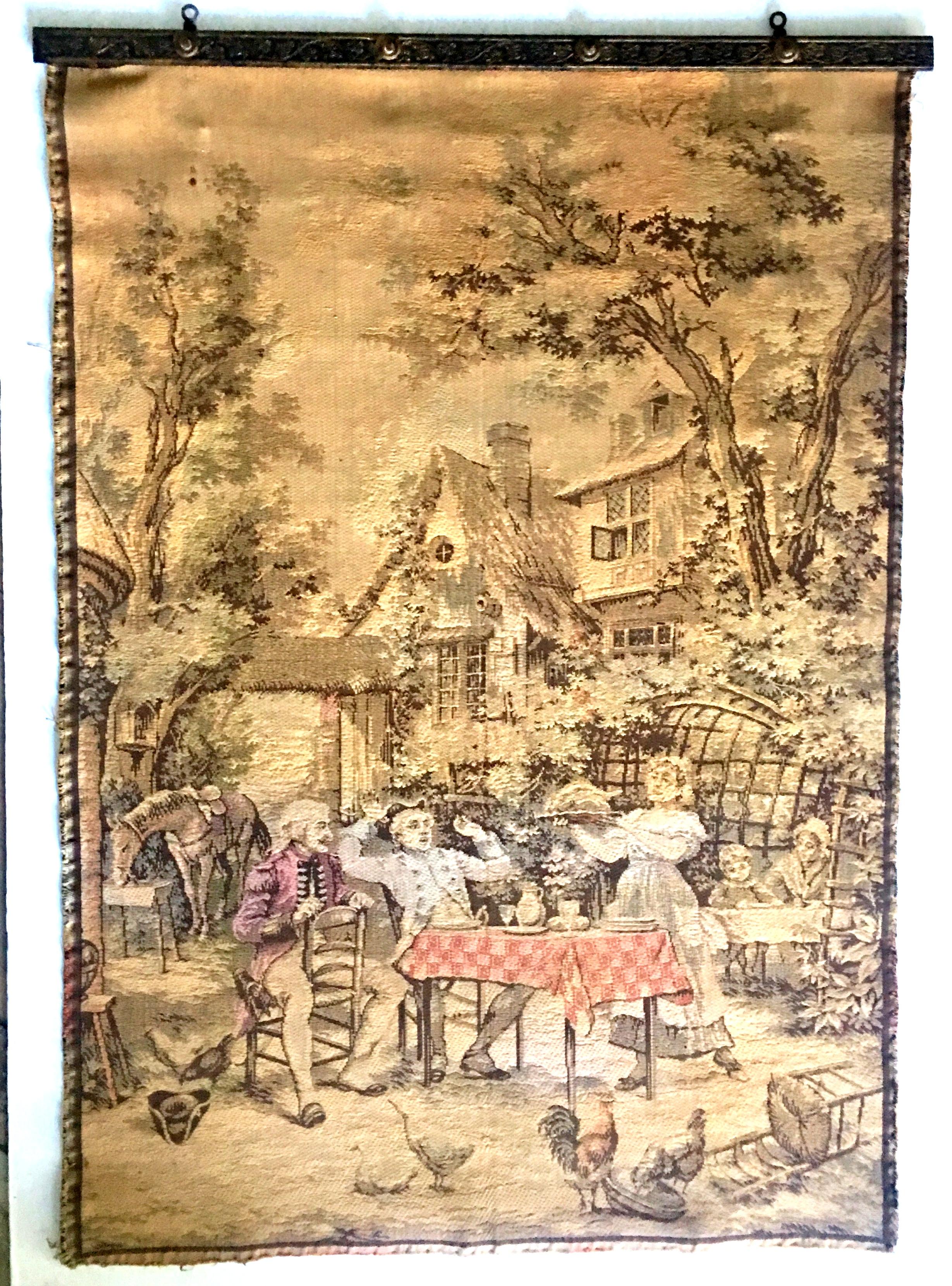 Mid- 20th Century French Aubusson Style Hanging Wall Tapestry. Features a golden, green, red, and orange hue 18th Century French Country Dinner Party Scene. Mounted on a bronze reposse two hole hanging frame. Signed on the underside, Made In France