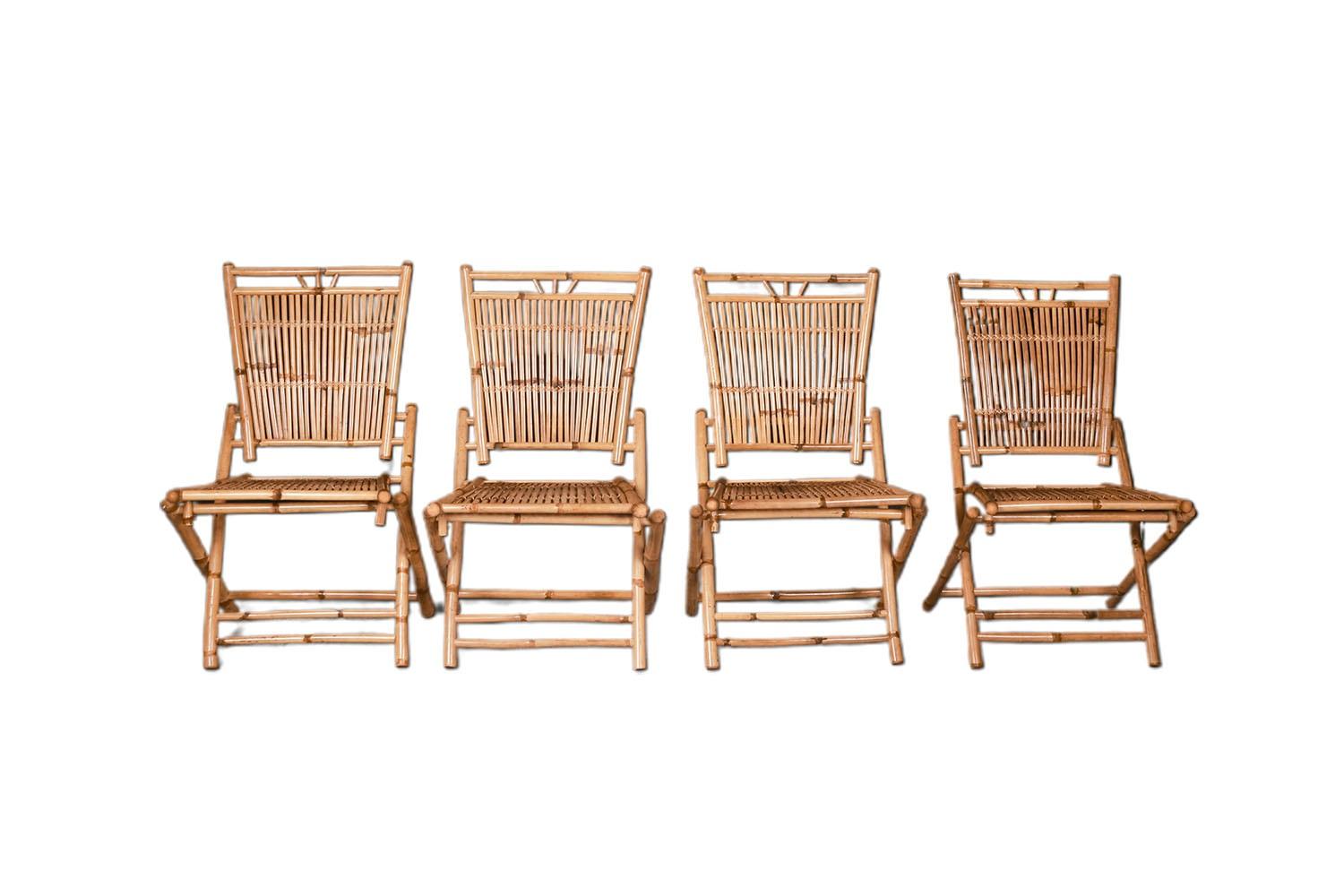 A set of four beautiful vintage mid century bamboo and rattan folding side chairs for indoor or outdoor use. Features X-form legs with stretchers/ foot rests and have comfortable slatted seats and backrests. The chairs are lightweight and fold flat