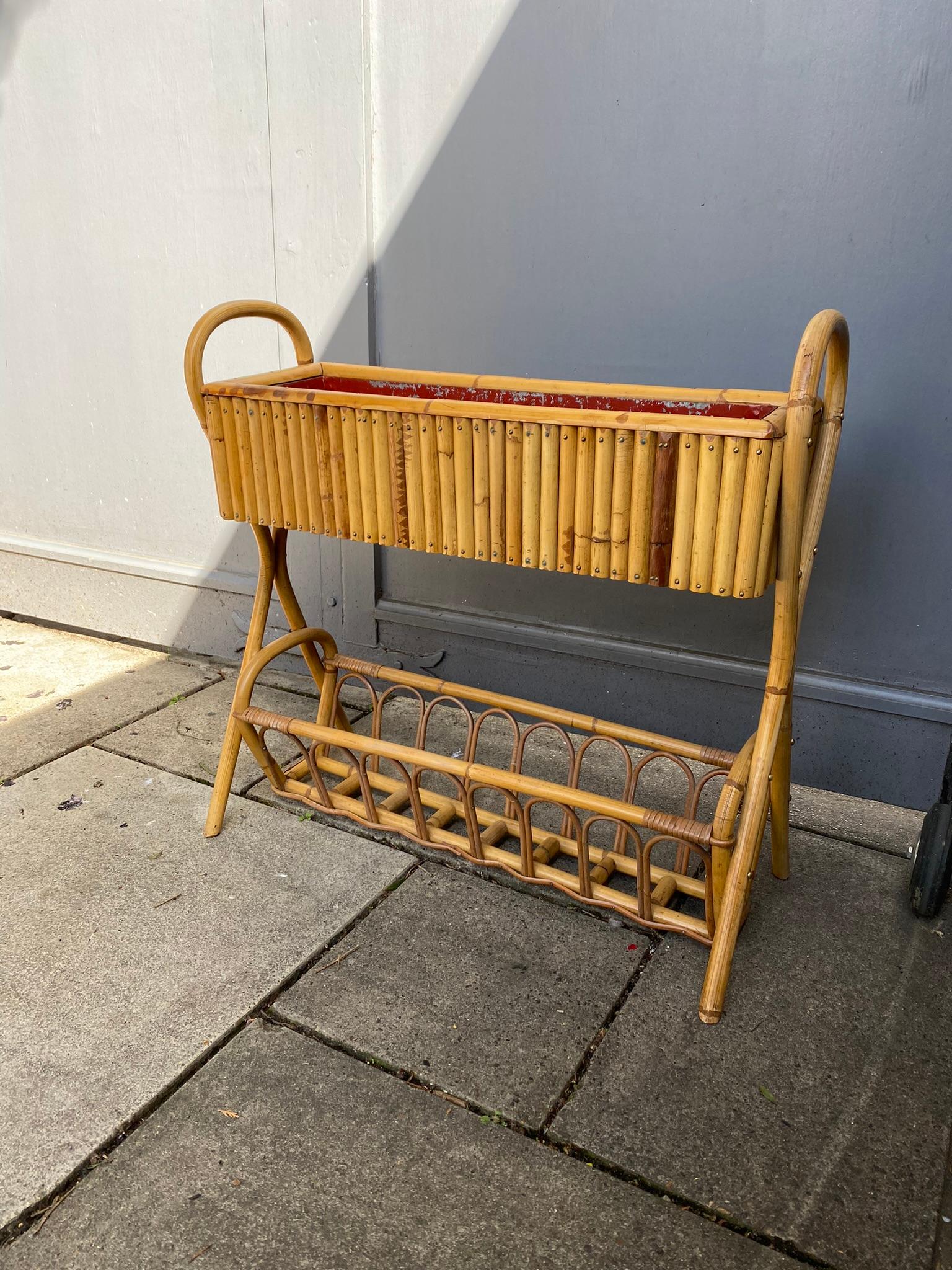 Pretty French bamboo / rattan jardinière planter. Constructed from a rattan frame with decorative bamboo vertical uprights.

The two-tier design has an open shelf on bottom to hold additional pots.

Inside the trough is a red metal liner with