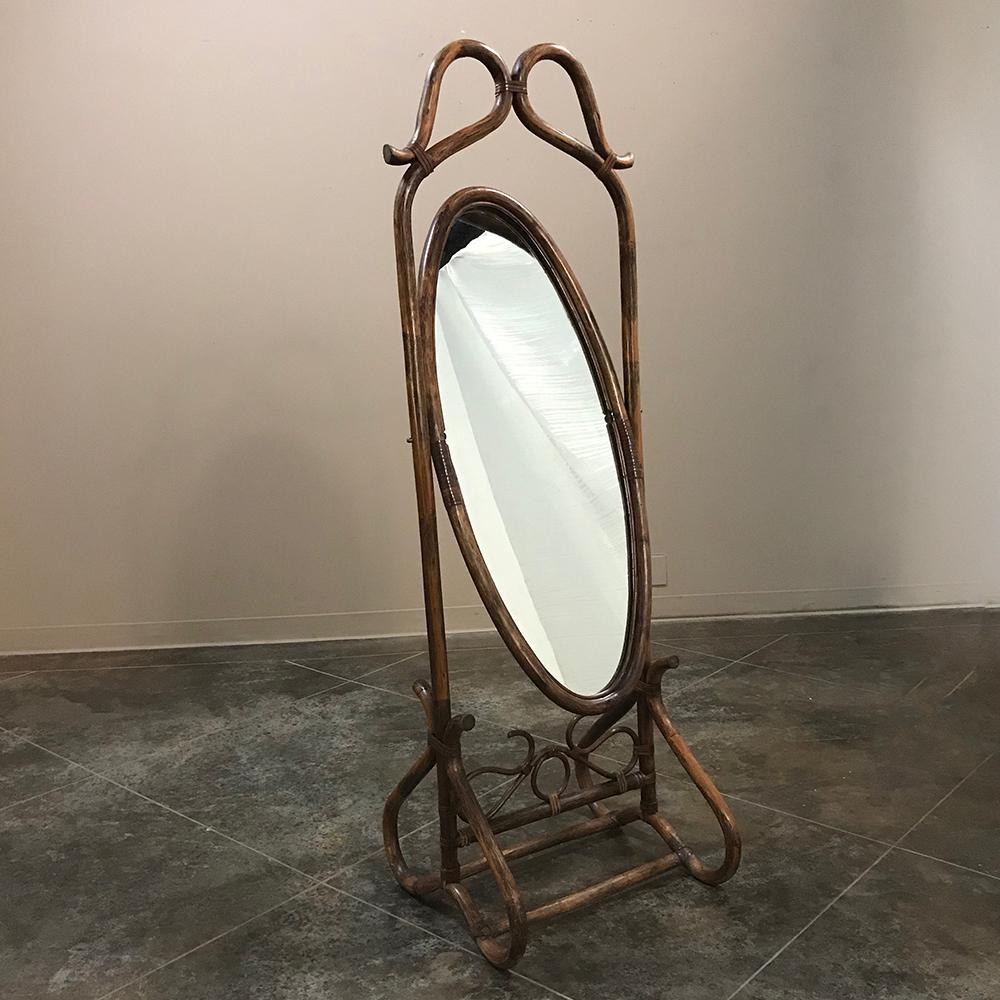 Featuring a full length, tilting oval dressing mirror, this elegant midcentury French Bentwood Cheval Dressing Mirror was literally fashioned by steaming and bending the wood to create the fanciful scroll shapes that lend an air of grace and