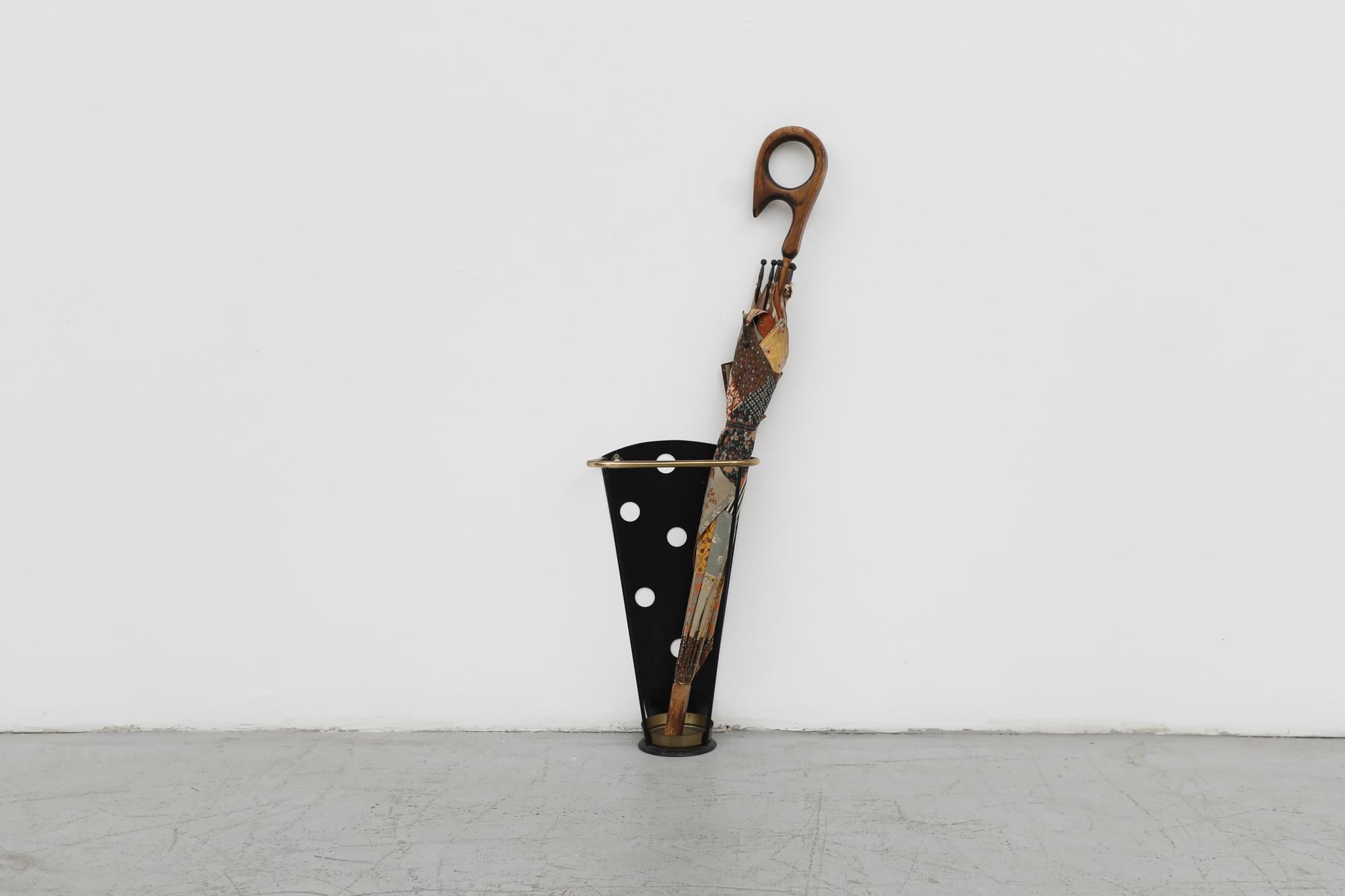 Fun, Mid-Century, 1950s French wall mounted black enameled polkadot umbrella stand with brass accent details. The back has a cut-out 'polkadots' design and brass trim with a removable brass drip tray. Perfect for a classy upscale entry way! In