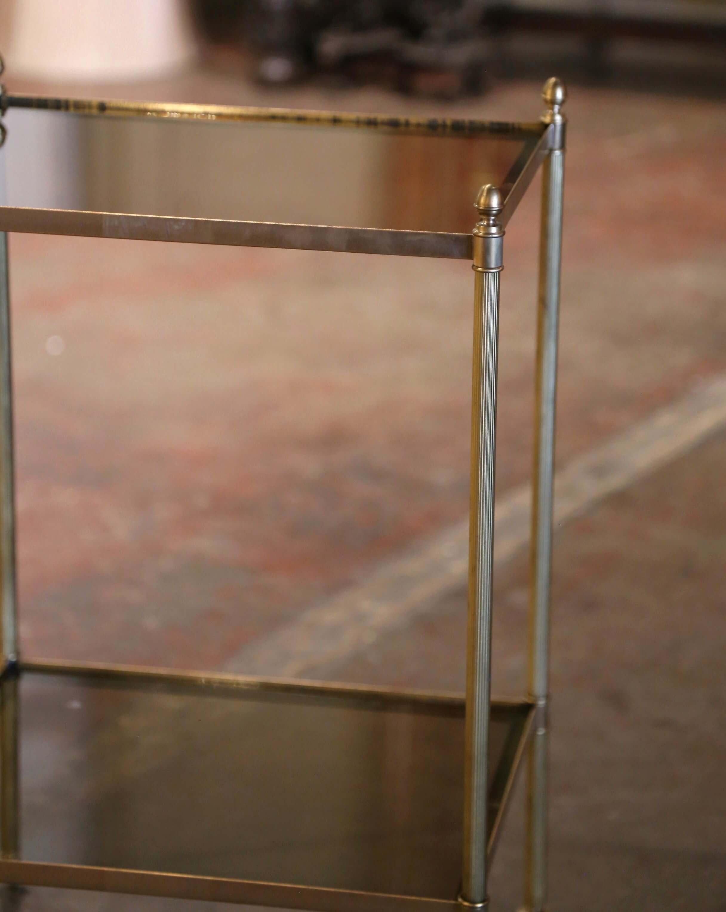 This elegant antique side table was crafted in France circa 1950. Rectangular in shape and attributed to Maison Jansen in Paris, the delicate brass table stands on round and spline legs ending with bun feet at the base, and dressed with decorative