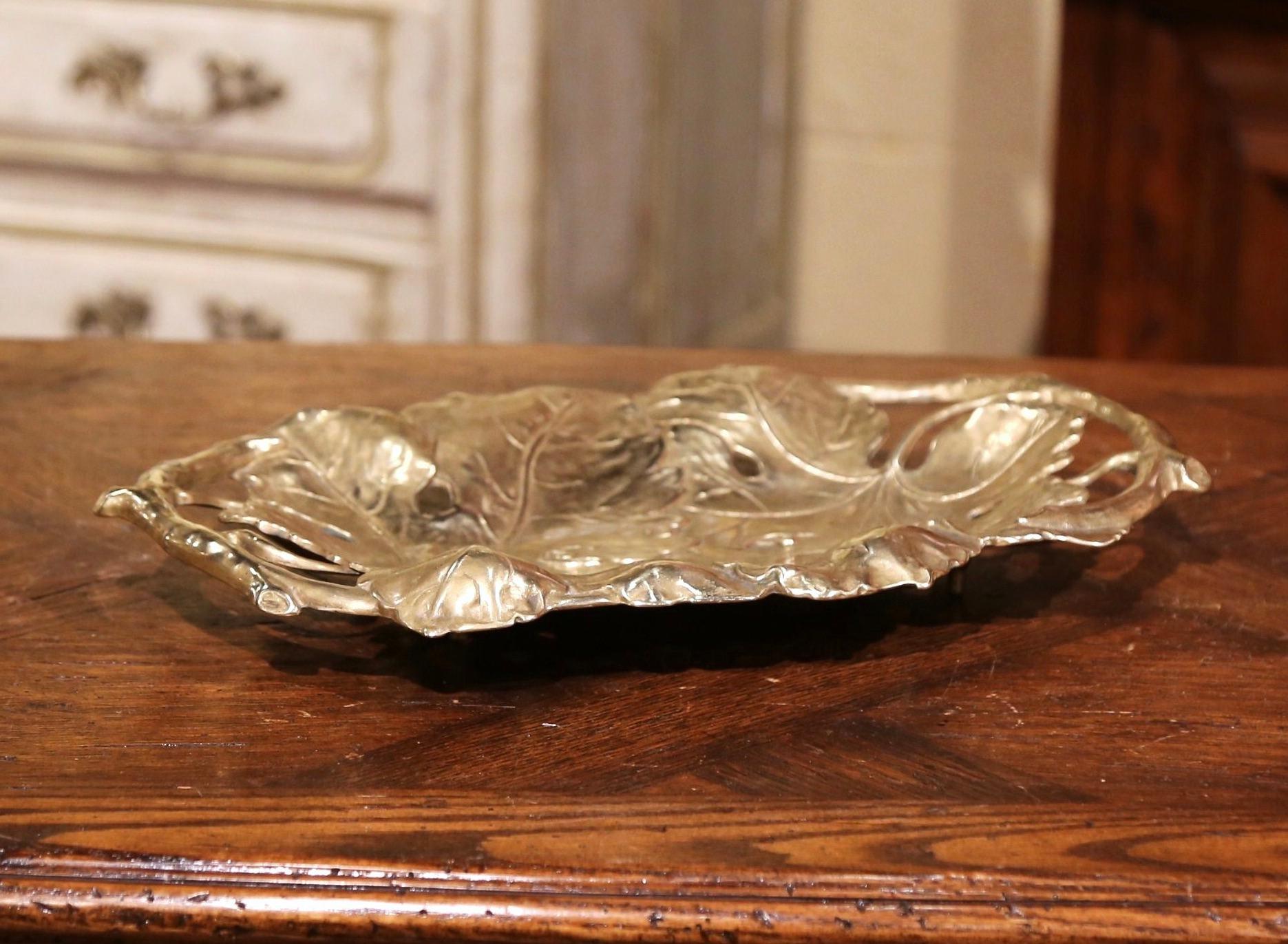 Display your sweet or crackers in this decorative antique dish from France; crafted circa 1880 and made of solid brass, the platter features exquisite and detailed repousse vine and leaf decor including tree root handles. The ornate vide-poche is in