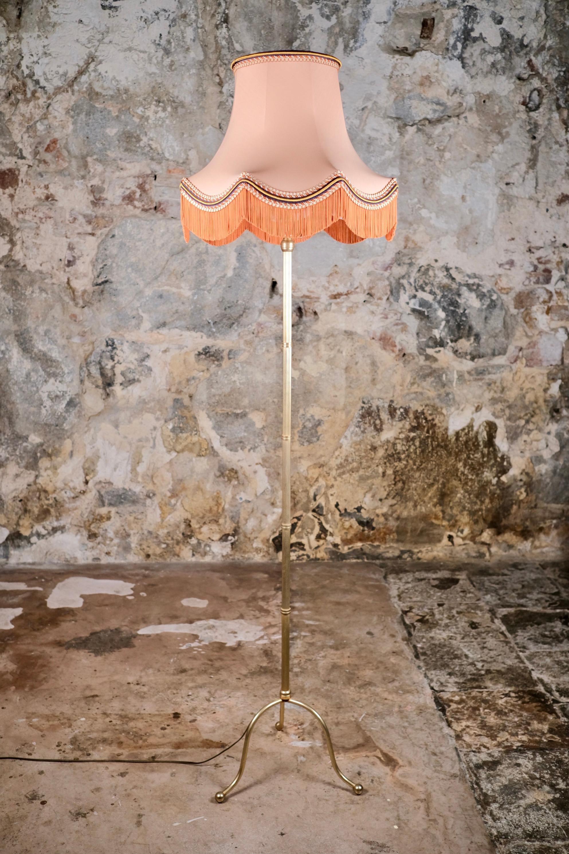 Una lampada da terra francese bella e di carattere, della metà del XX secolo, che mostra un sottile spirito Art Déco. Questo elegante pezzo presenta una struttura sottile in ottone delicatamente patinato che poggia su una raffinata base a treppiede