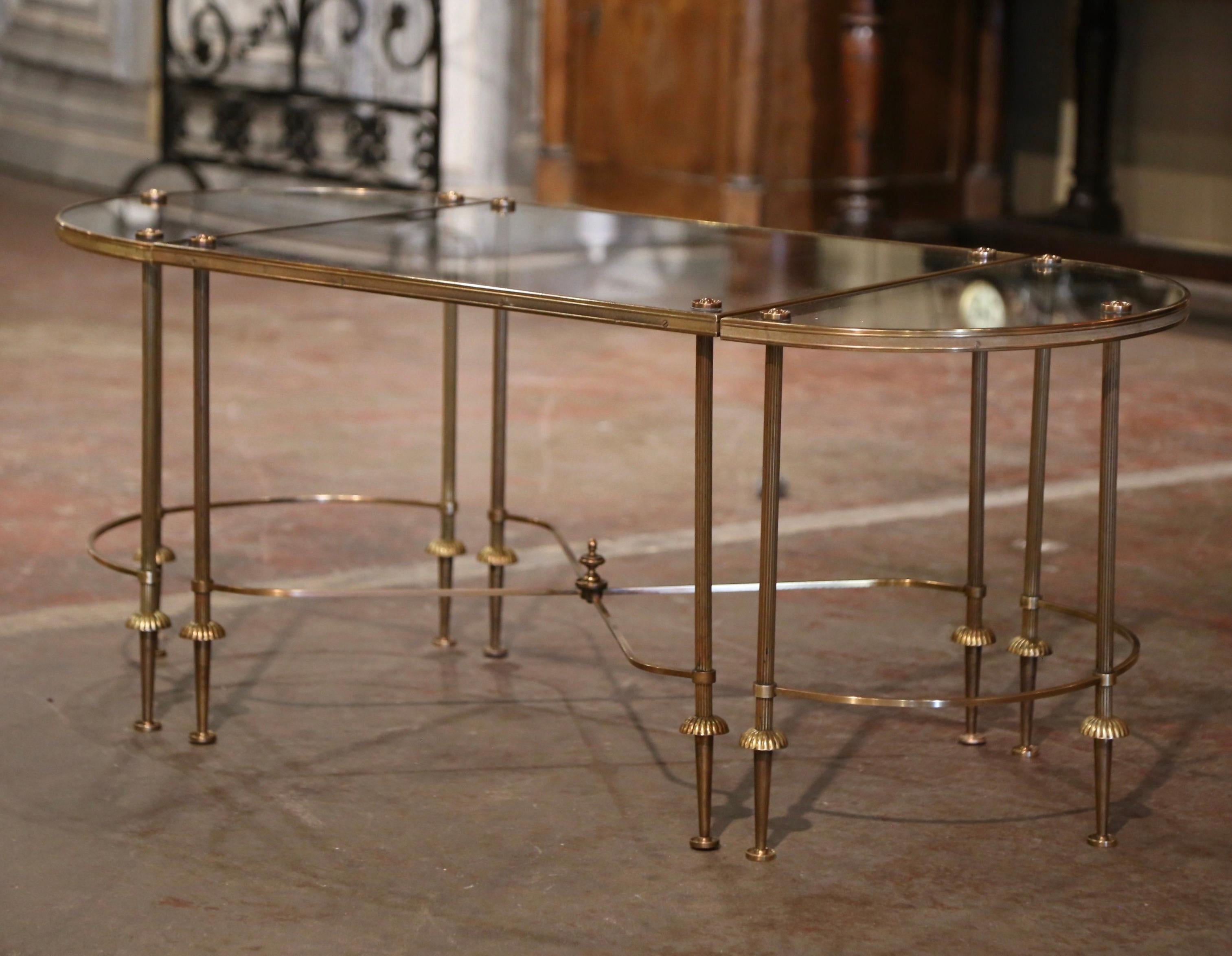 This mid-century three-piece oval cocktail table was created in Paris France circa 1950. Attributed to Maison Baguès and built of brass, the table features three separate elements: a square center table and two demi-lune ends. Each section stands on