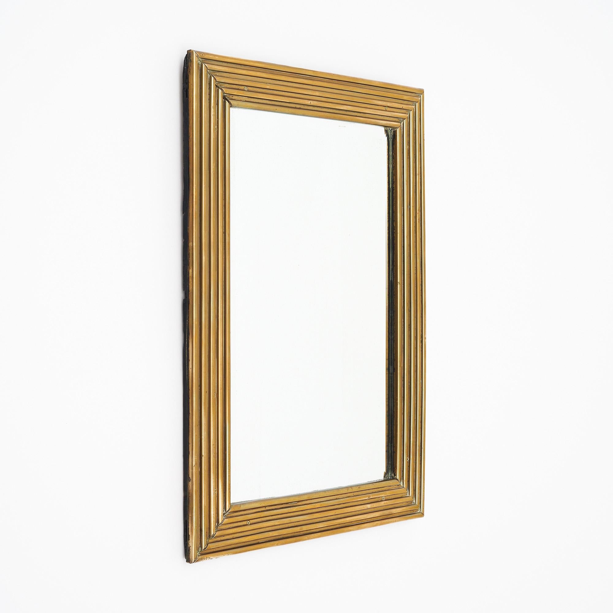 Specchio della metà del secolo scorso in Francia con cornice in ottone e specchio centrale originale. Lo specchio centrale è smussato sui bordi. La cornice ha un meraviglioso design a gradini. Questo pezzo è in eccellenti condizioni vintage - le