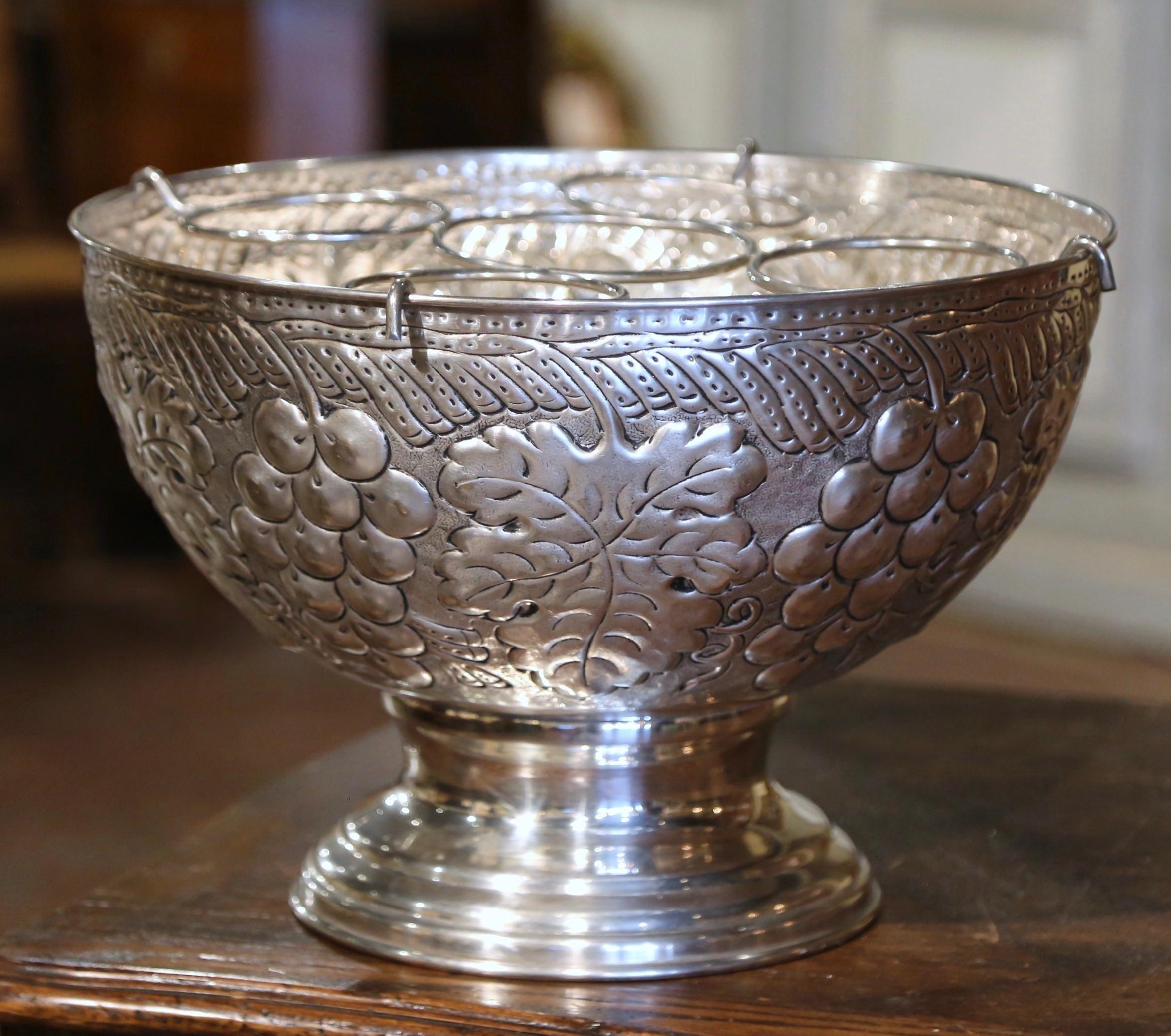 Serve your wine or champagne in style with this elegant cooler bucket. Crafted in France circa 1980 and circular in shape, the bowl features intricate repousse grape and vine motifs throughout. Inside the bucket, a five bottle removable tray