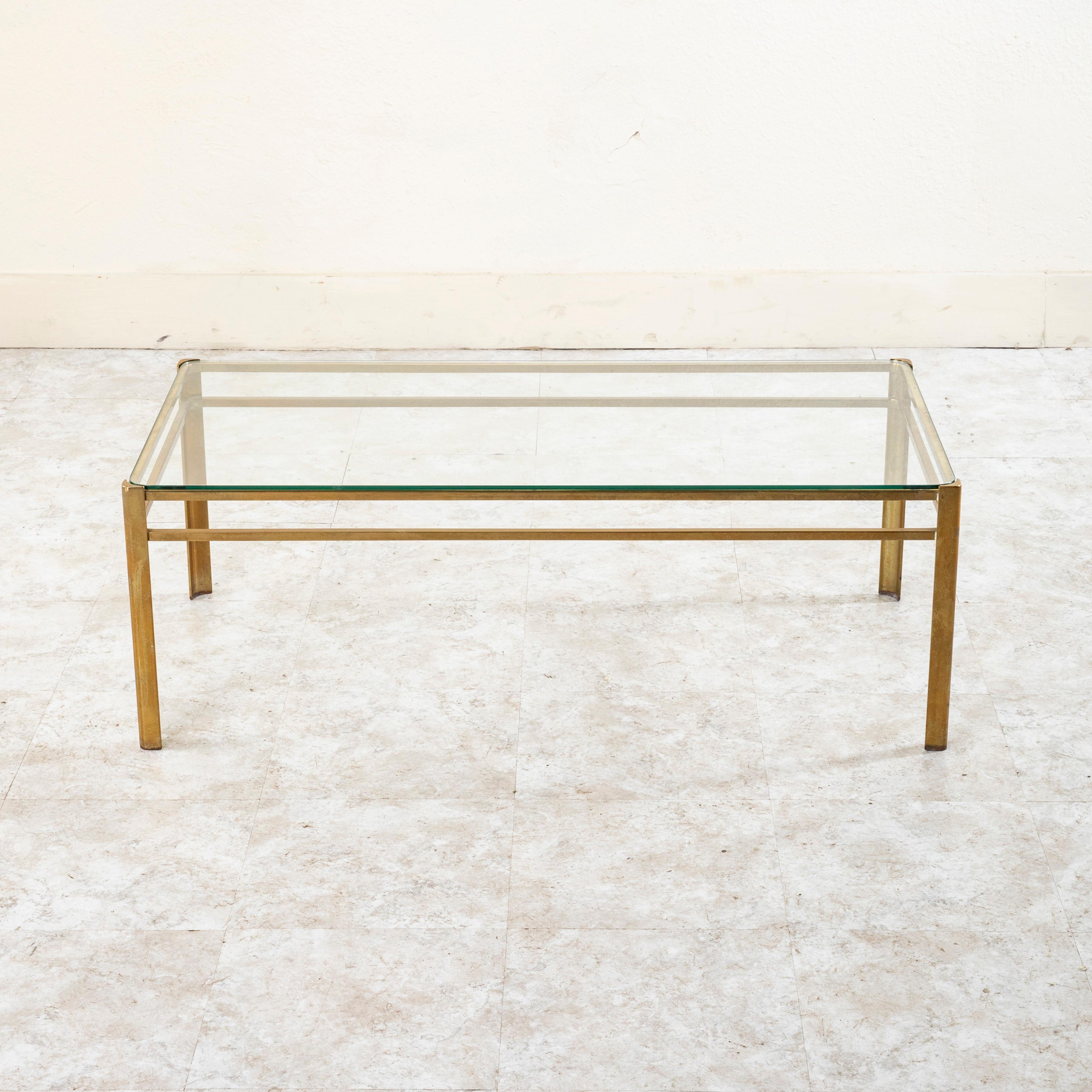 This mid-century bronze and glass coffee table or cocktail table is attributed to Jacques Quinet. The renowned twentieth century French designer drew his inspiration from the neoclassical aesthetic in architecture and interpreted it in his own