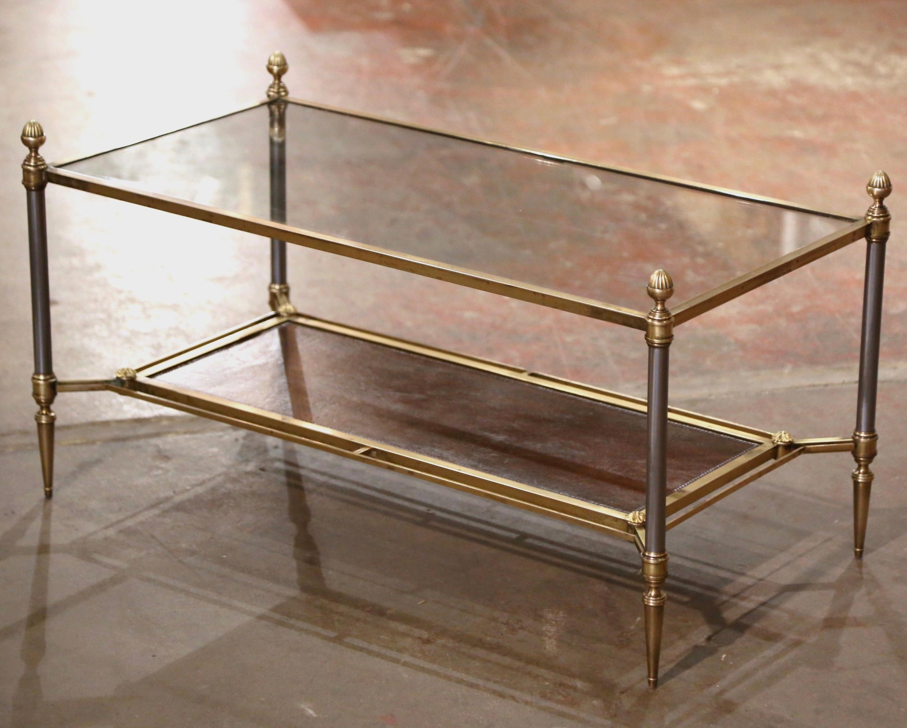 Decorate a living room or den with this elegant antique coffee table. Created in Paris, France, circa 1950 by Maison Jansen, the clean line frame is made of brushed steel, bronze and brass; it features round legs ending with tapered feet, and is