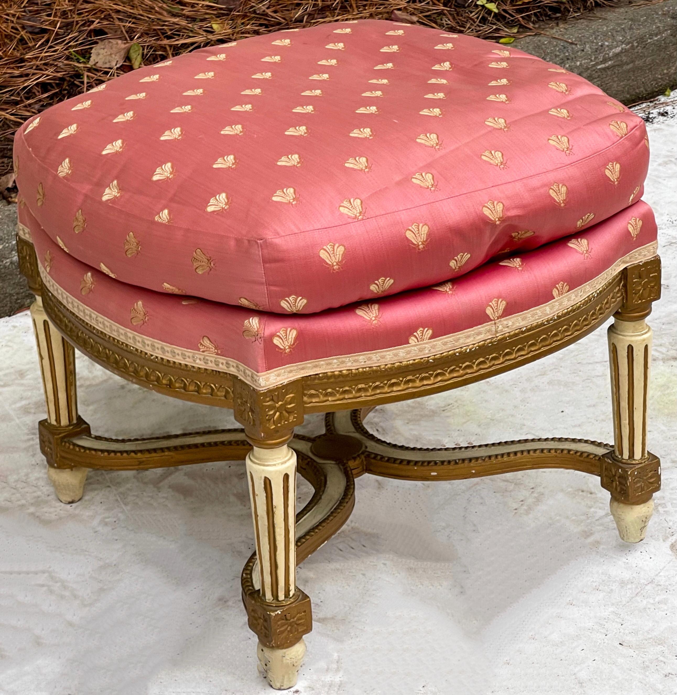 This is a lovely ottoman! It is a French carved giltwood and painted ottoman in vintage pink Napoleonic bee fabric. It is a versatile size and show some age wear to the finish.