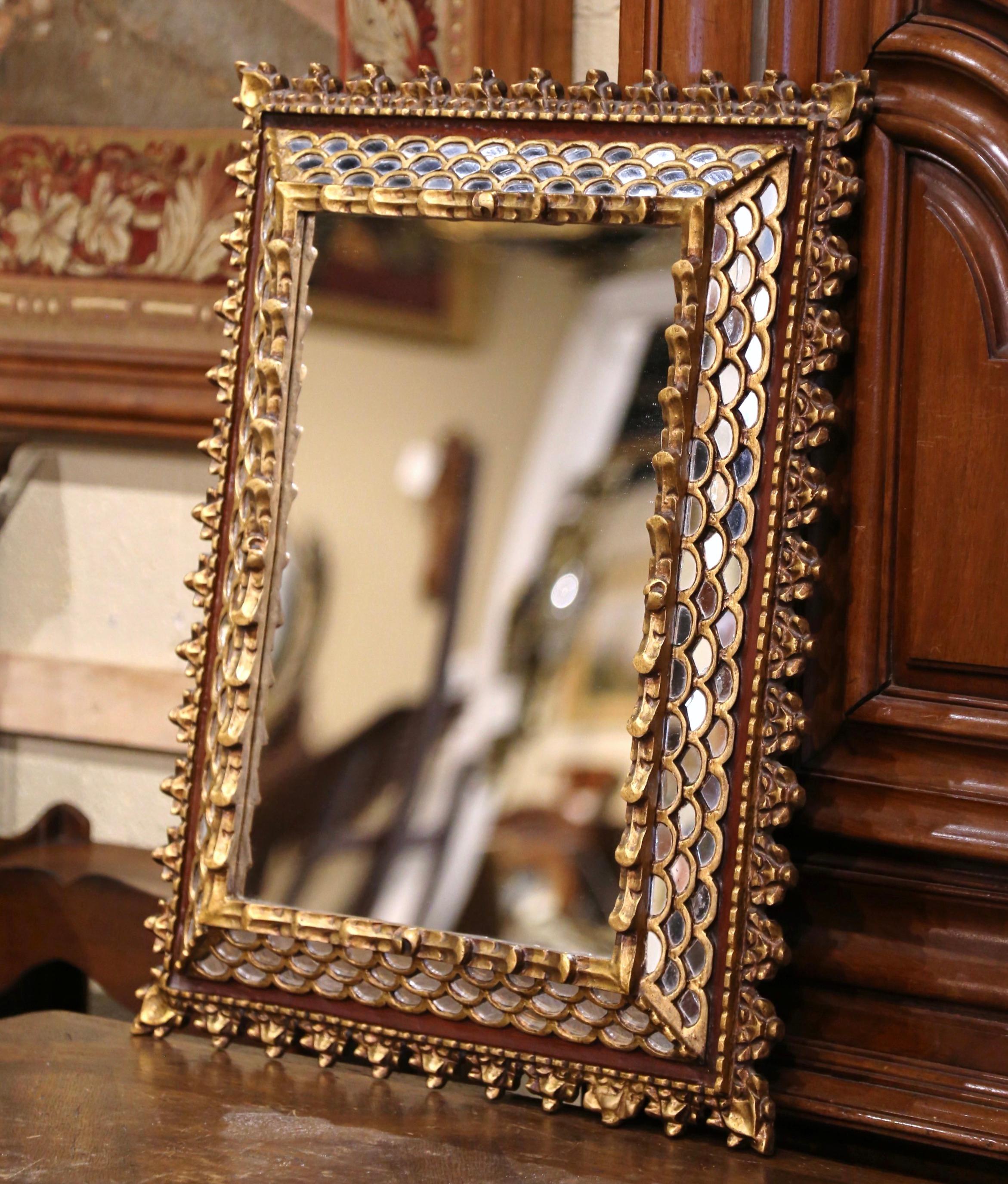 This elegant vintage sunburst mirror was crafted in France, circa 1960. Rectangular in shape and decorated with carved scalloped edges around the frieze frame, the antique wall mirror features a raised center mercury glass set inside; the four sides