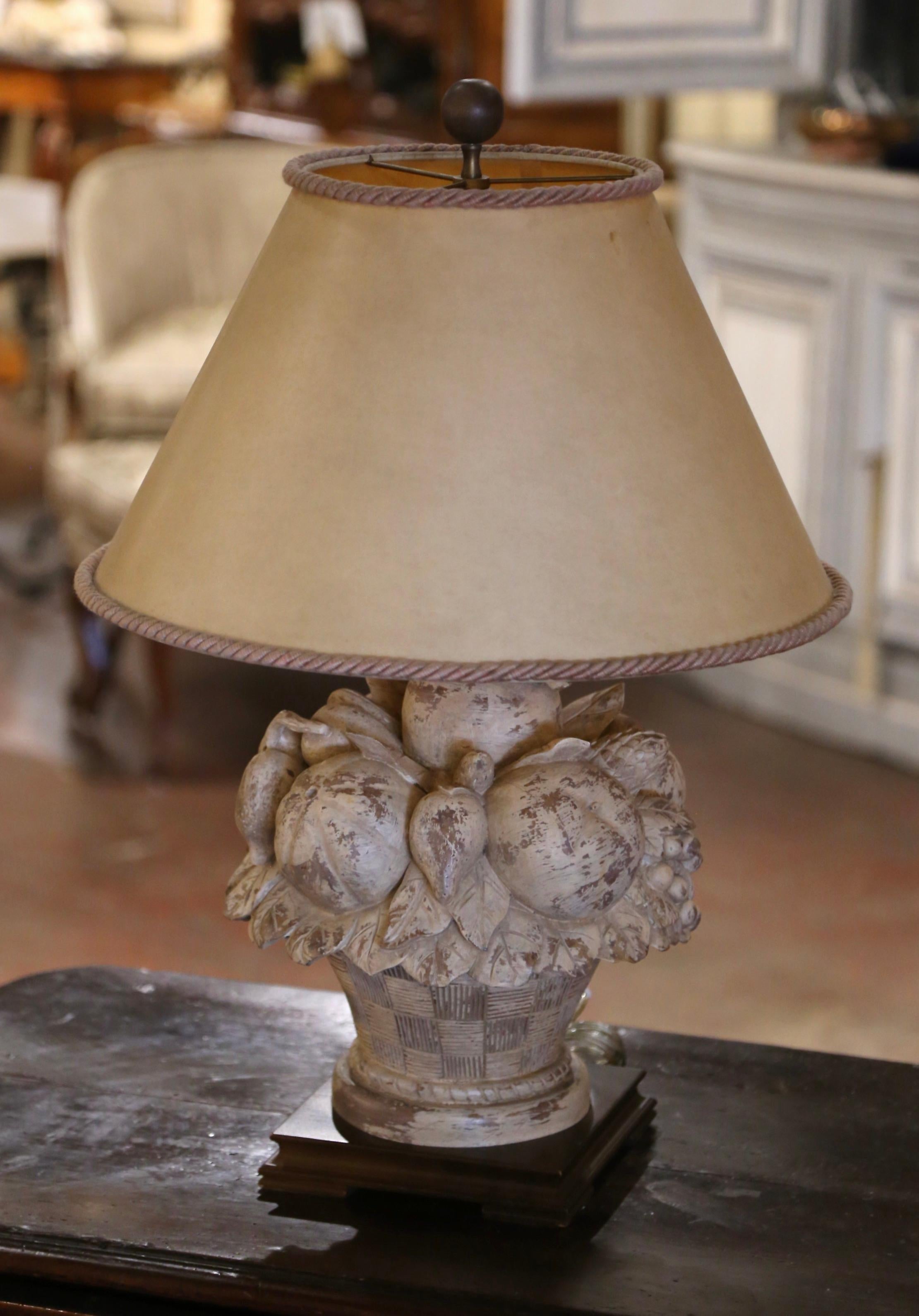 Realza tu mesa o consola con esta elegante lámpara de madera tallada de una sola luz, adornada con un encantador despliegue de frutas y follaje. Fabricada en Francia hacia 1970, la escultura descansa sobre una base cuadrada, que presenta una cesta