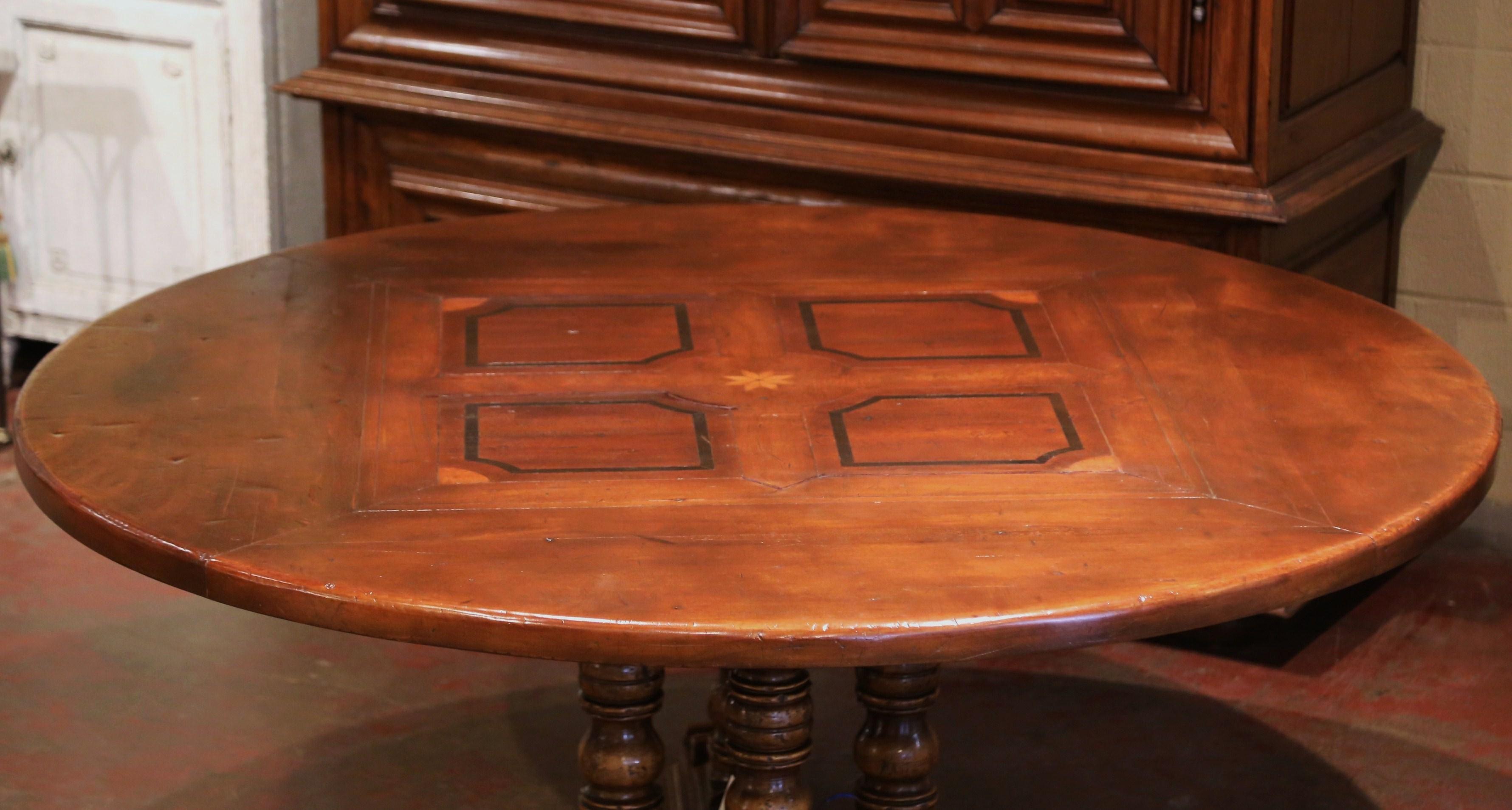 Crafted in the Pyrenees mountains of France half a century ago with 18th and 19th century old timber, the elegant six foot round table stands on a sturdy four hand turned columns pedestal base, supported by flat, hand carved feet for ultimate