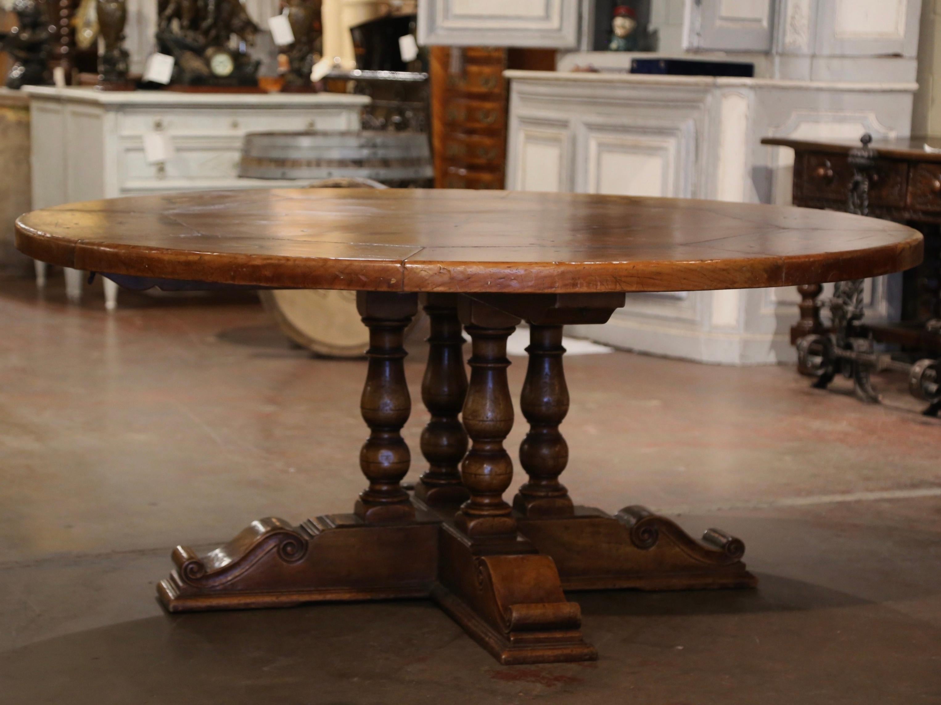 Crafted in the Pyrenees mountains of France half a century ago with 18th and 19th century old timber, the elegant six foot round table stands on a sturdy four hand turned columns pedestal base, supported by flat, hand carved feet for ultimate