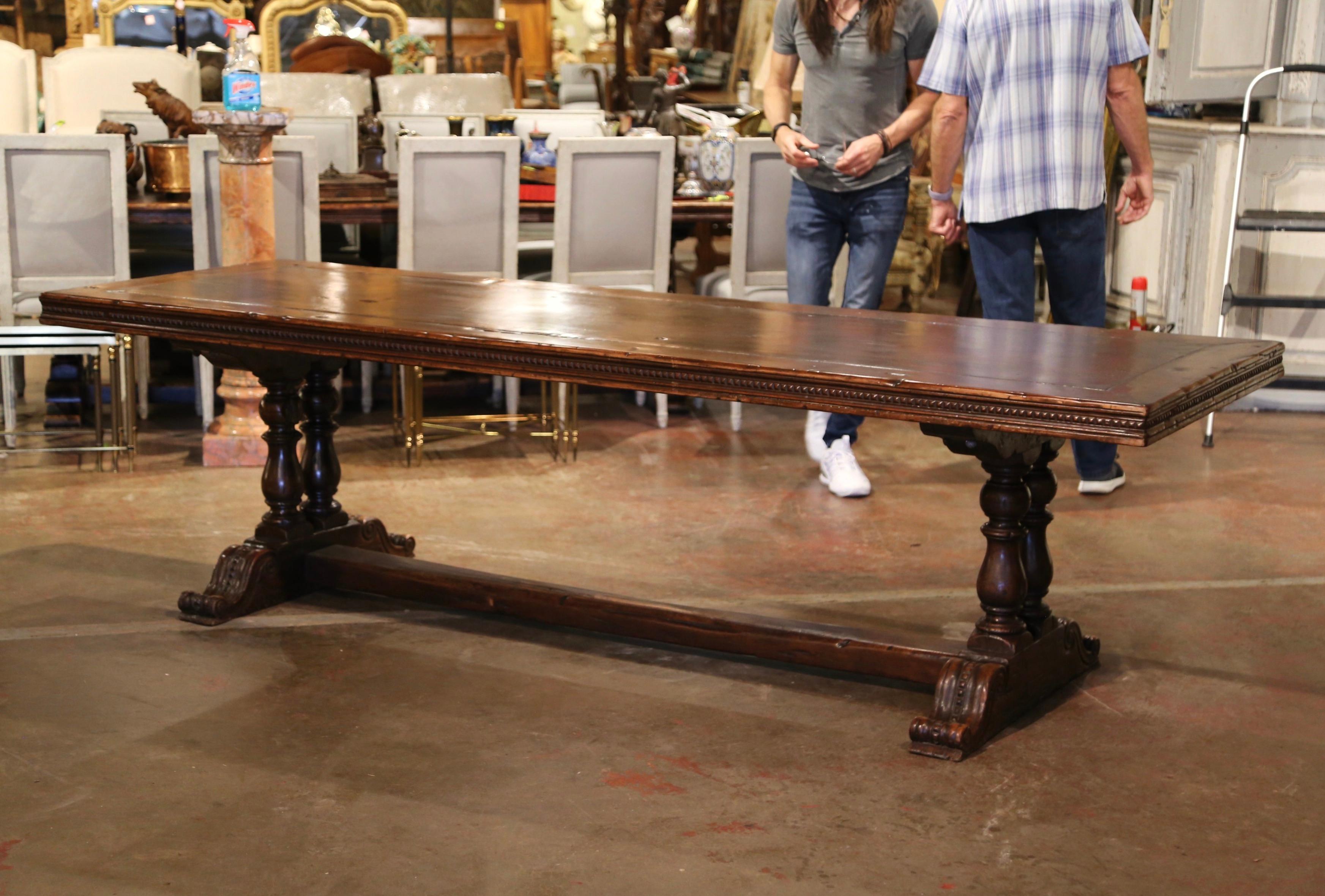 This large antique dining room table was crafted in southwest France, near the Spanish and French border. Built with 18th century walnut timber, the 9 foot table stands on two hand carved baluster legs ending with shoe base, and connected with a