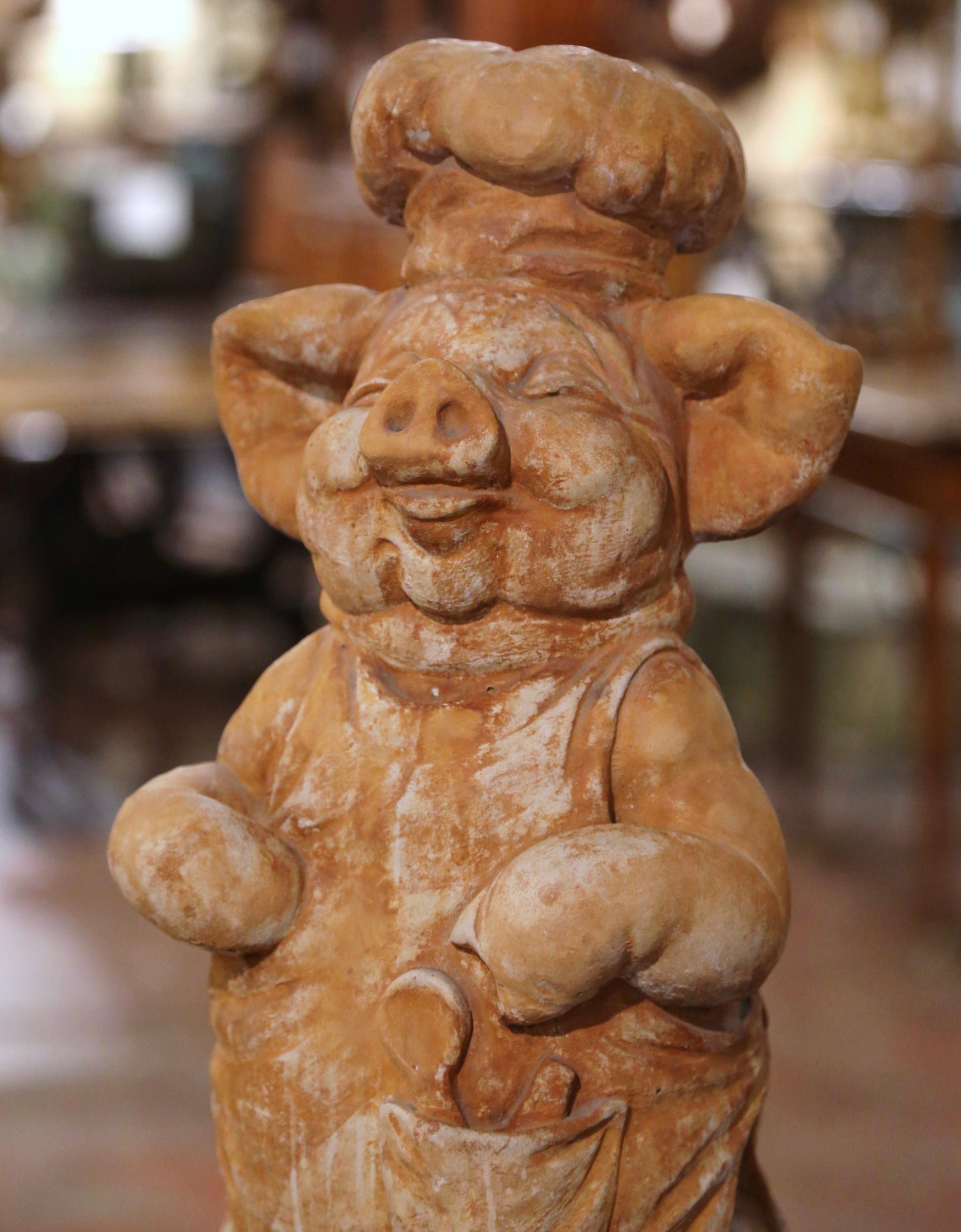 Decorate a kitchen counter or patio with this antique stone pig sculpture. Crafted in France circa 1970 and carved of concrete, the sculpture features a smiling pig standing on a round base. The tall cheerful pig composition is in excellent