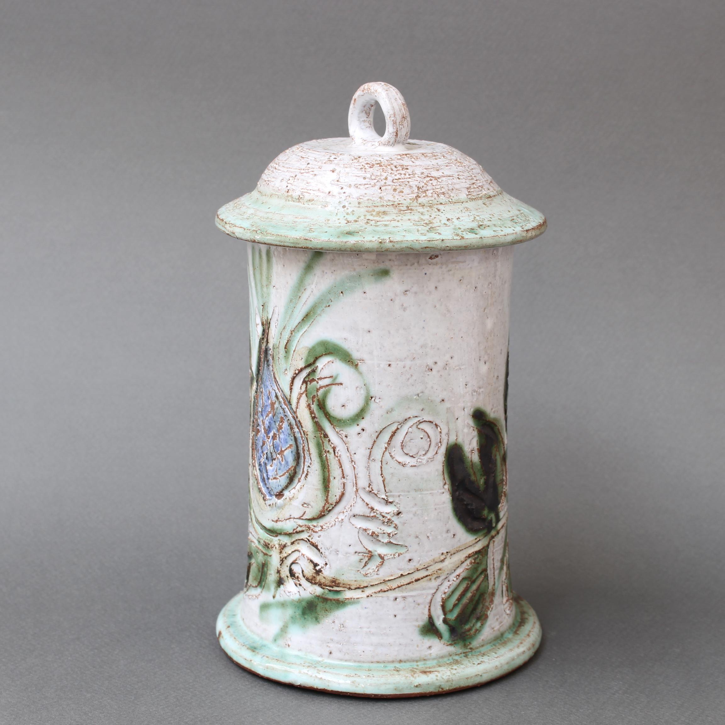 Mid-century French ceramic apothecary jar by Albert Thiry (circa 1960s). A delightful piece with Thiry's signature style, chalk-white base with blue thistle and foliage painted motif. A charming bell-shaped cover tops the piece in a creamy white
