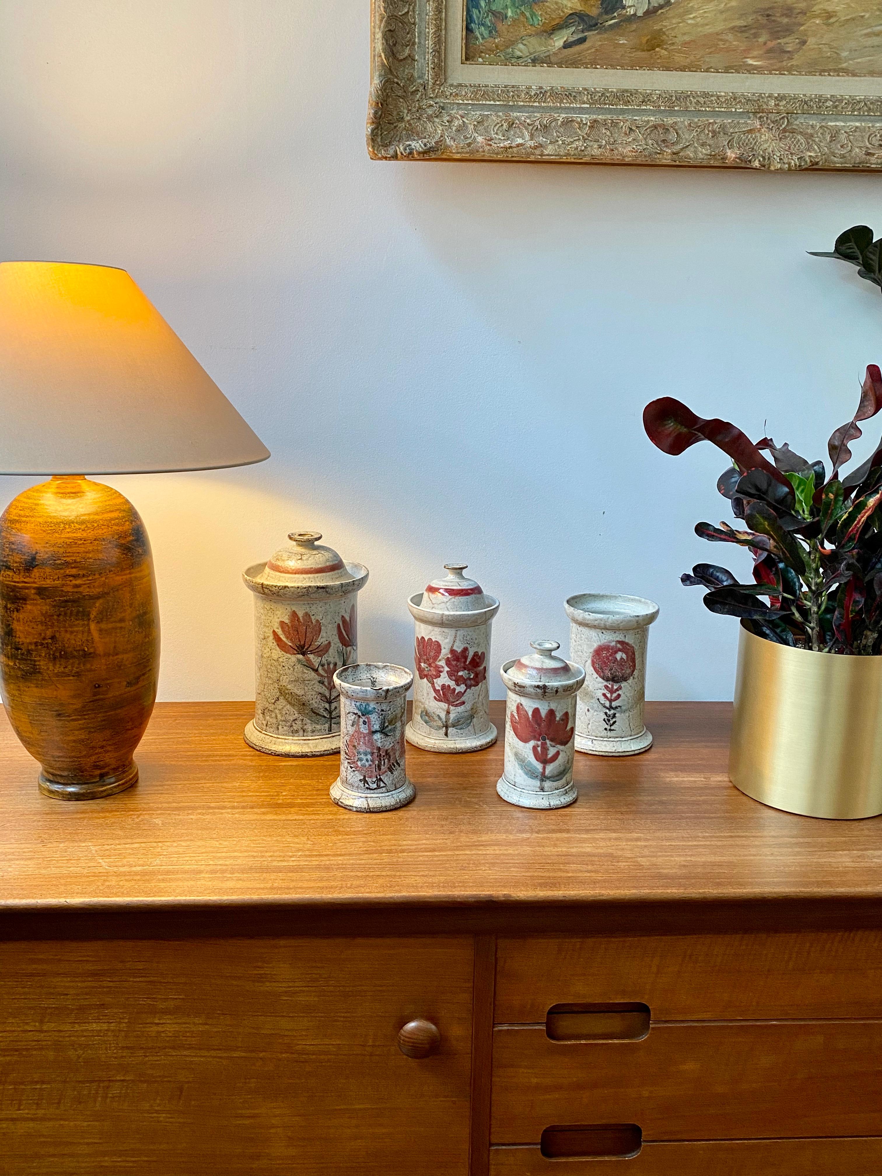 Midcentury French ceramic apothecary jar by Gustave Reynaud for Le Murier, circa 1950s. A seductive piece with Reynaud's signature style, chalk-white color with red flower and foliage painted motif. A charming bell-shaped cover with painted red band