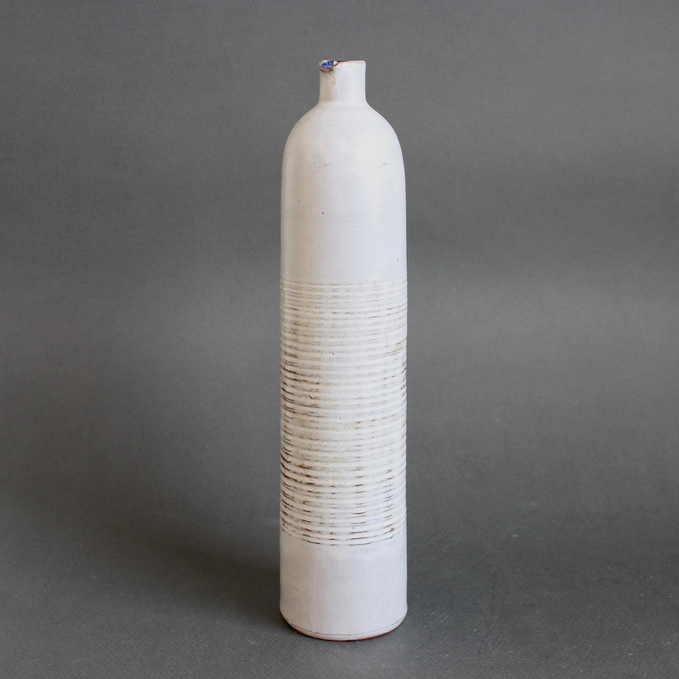 Vaso monofiore in ceramica a forma di bottiglia (1955-1965 circa) di Les Argonautes, Vallauris, Francia. Una forma elegante con una superficie bianca opaca e lattiginosa interrotta nella fascia centrale da un motivo testuale a linee con sfumature