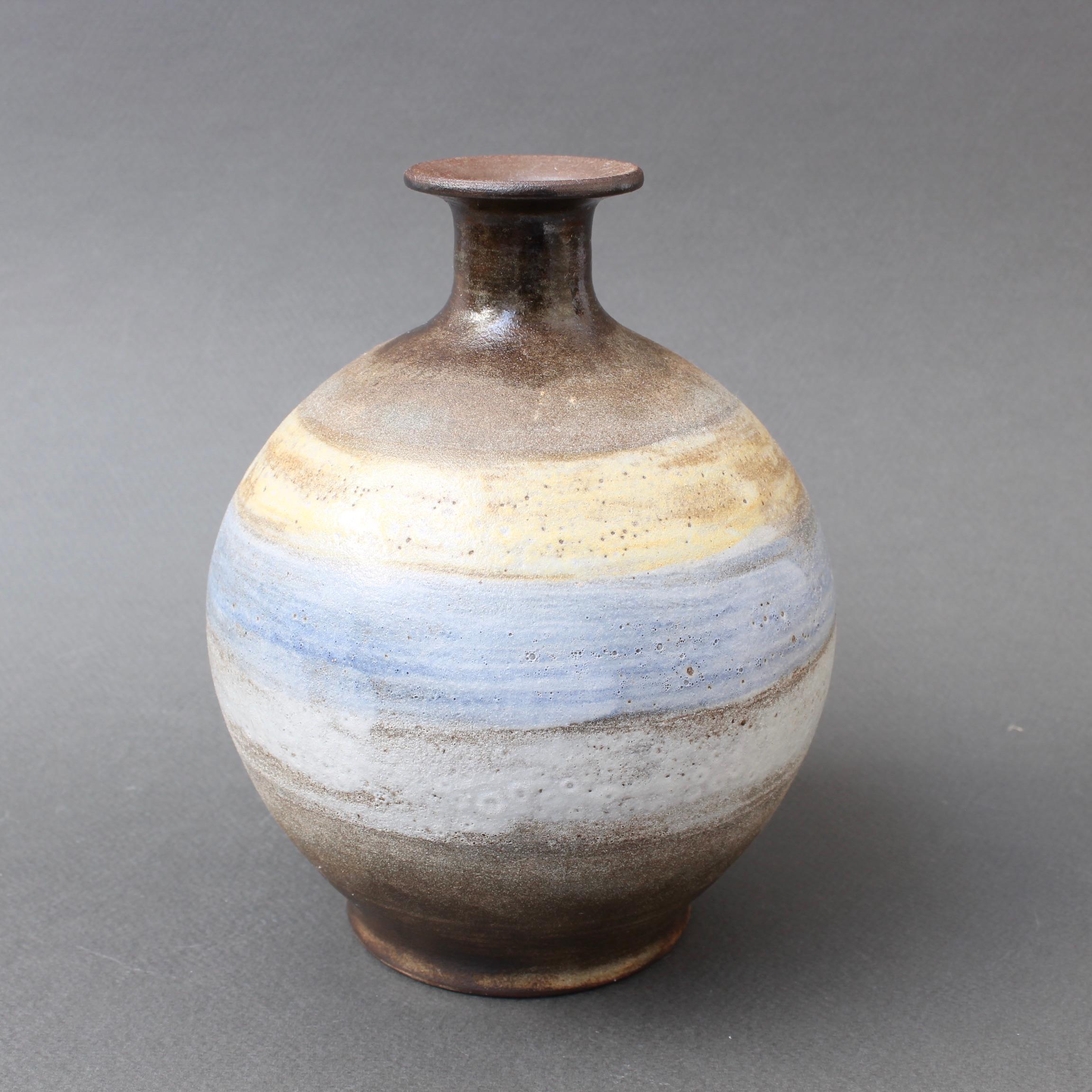 Ceramic decorative vase by Alexandre Kostanda, Vallauris, France, (circa 1960s). Kostanda's trademark natural clay and rustic style is enriched in this piece with ethereal painted rings like those that encircle planets in space. Their subtle hues