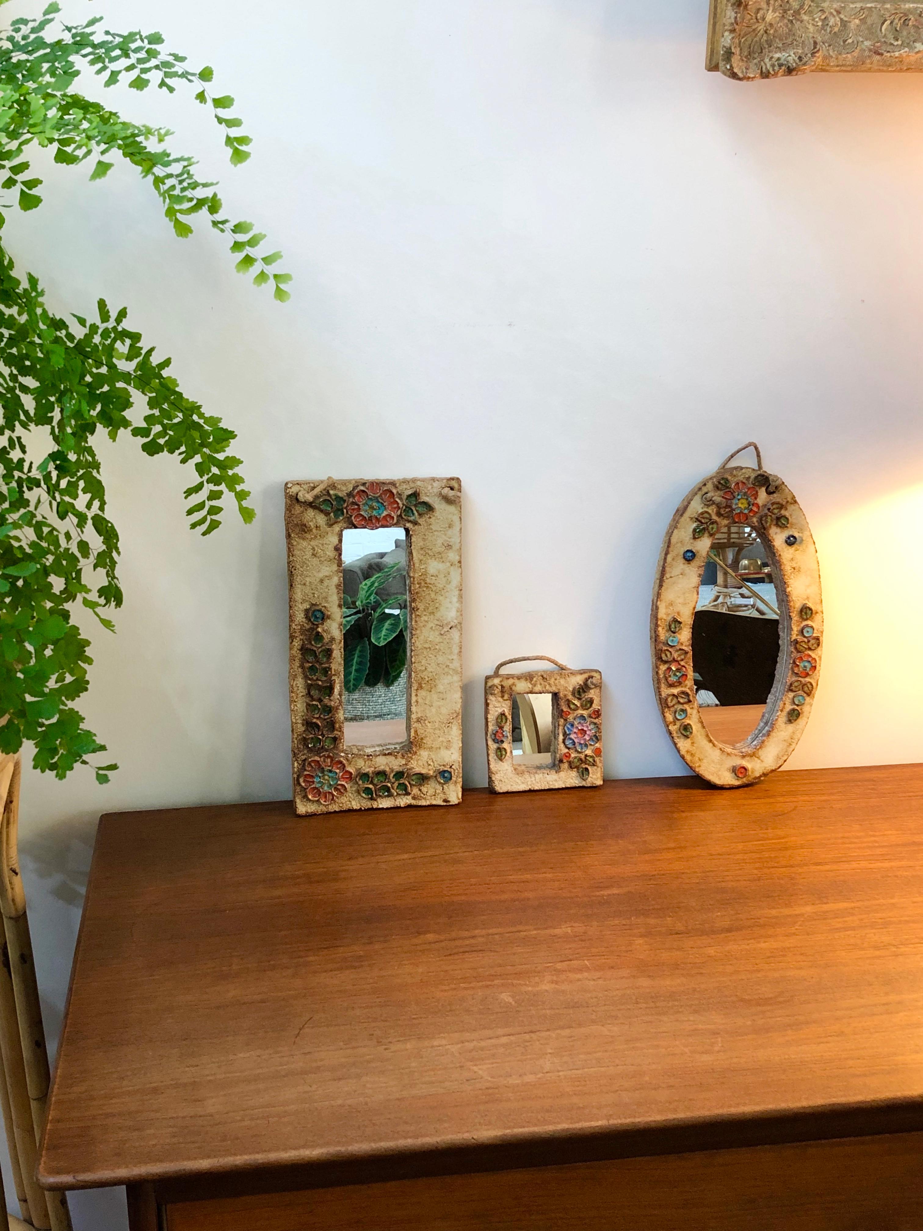 Ceramic flower-motif wall mirror with glazed leaves attributed to La Roue, Vallauris, France, circa 1960s. A charming, decorative small mirror with rustic but colorful details surrounding the narrow, rectangular mirror. In good vintage condition