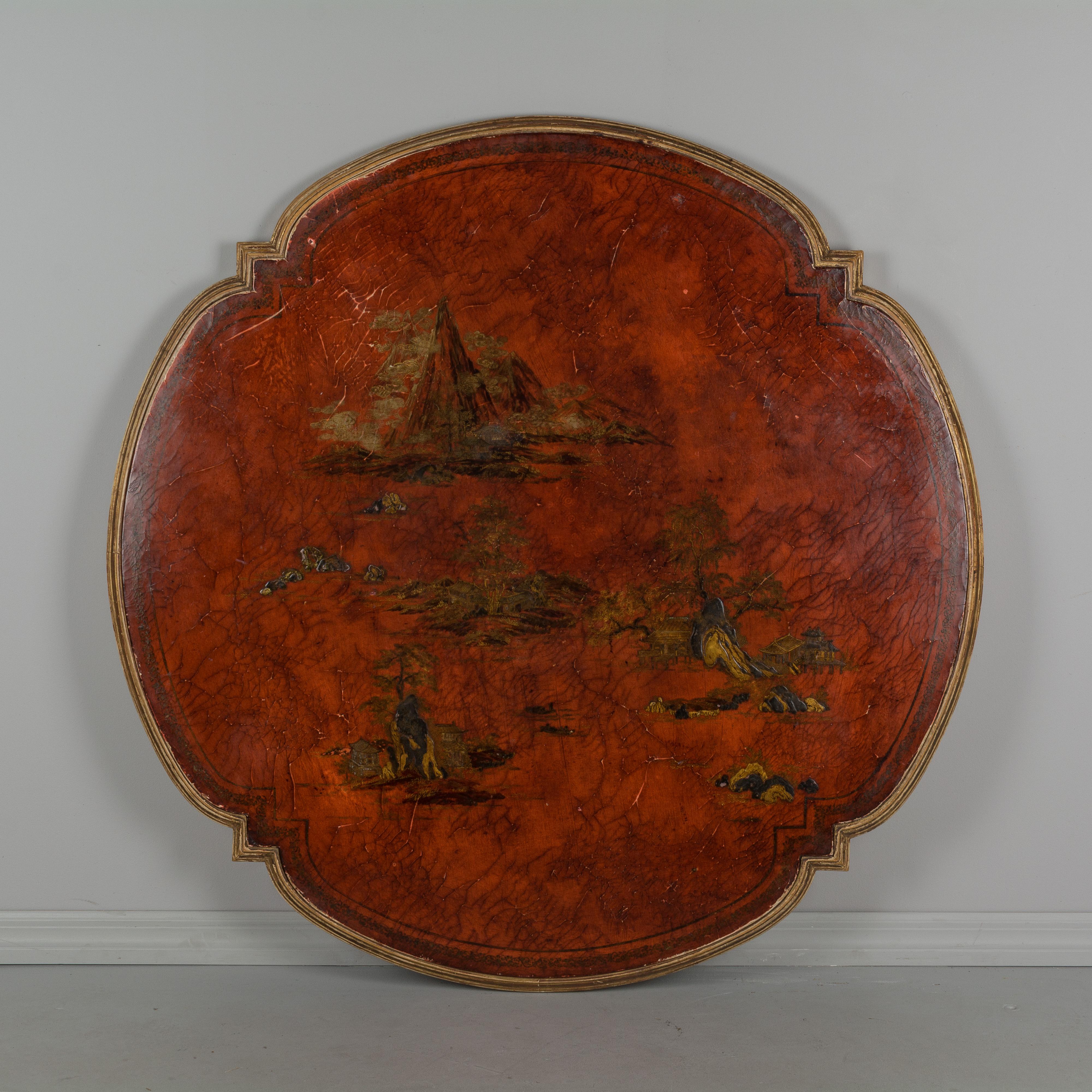 A French chinoiserie Guéridon, or center table, with parcel giltwood base and red lacquer top. Ornately carved base with gilded foliate relief on pale green ground. The top has landscape vignettes that are slightly raised and accented in gold.