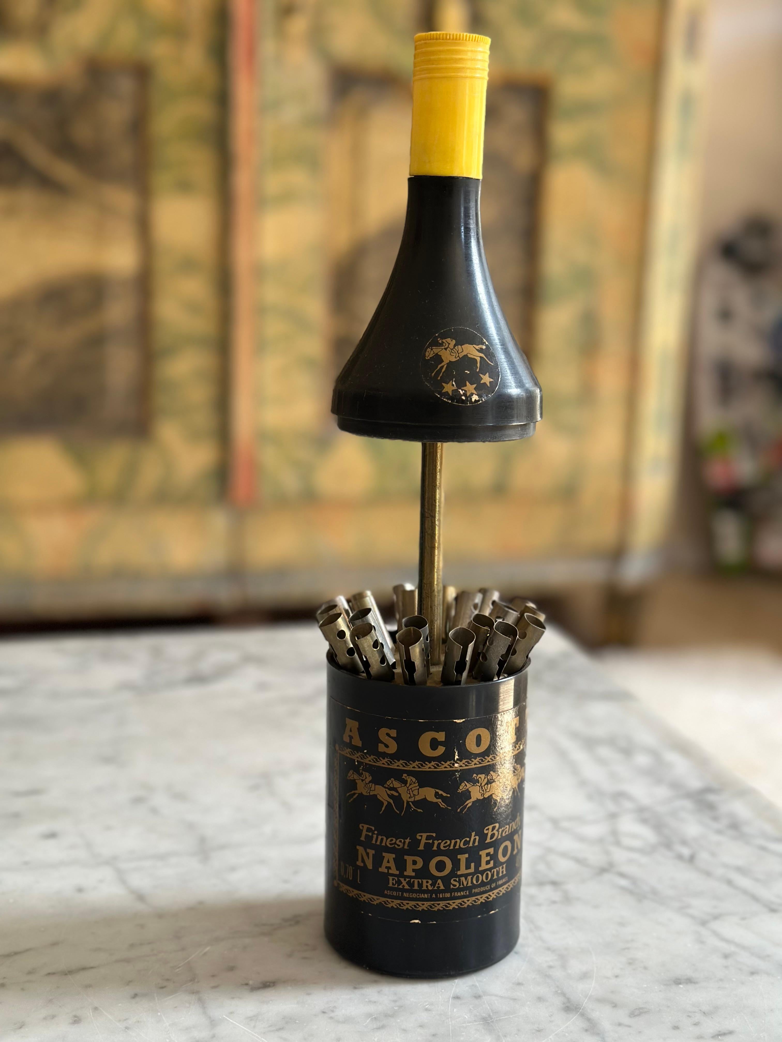 Ce distributeur de cigarettes excentrique et de collection a été fabriqué en France vers 1950 et capture l'esprit inimitable du style de vie du milieu du siècle d'après-guerre. Design/One en forme de bouteille de brandy, le distributeur est en