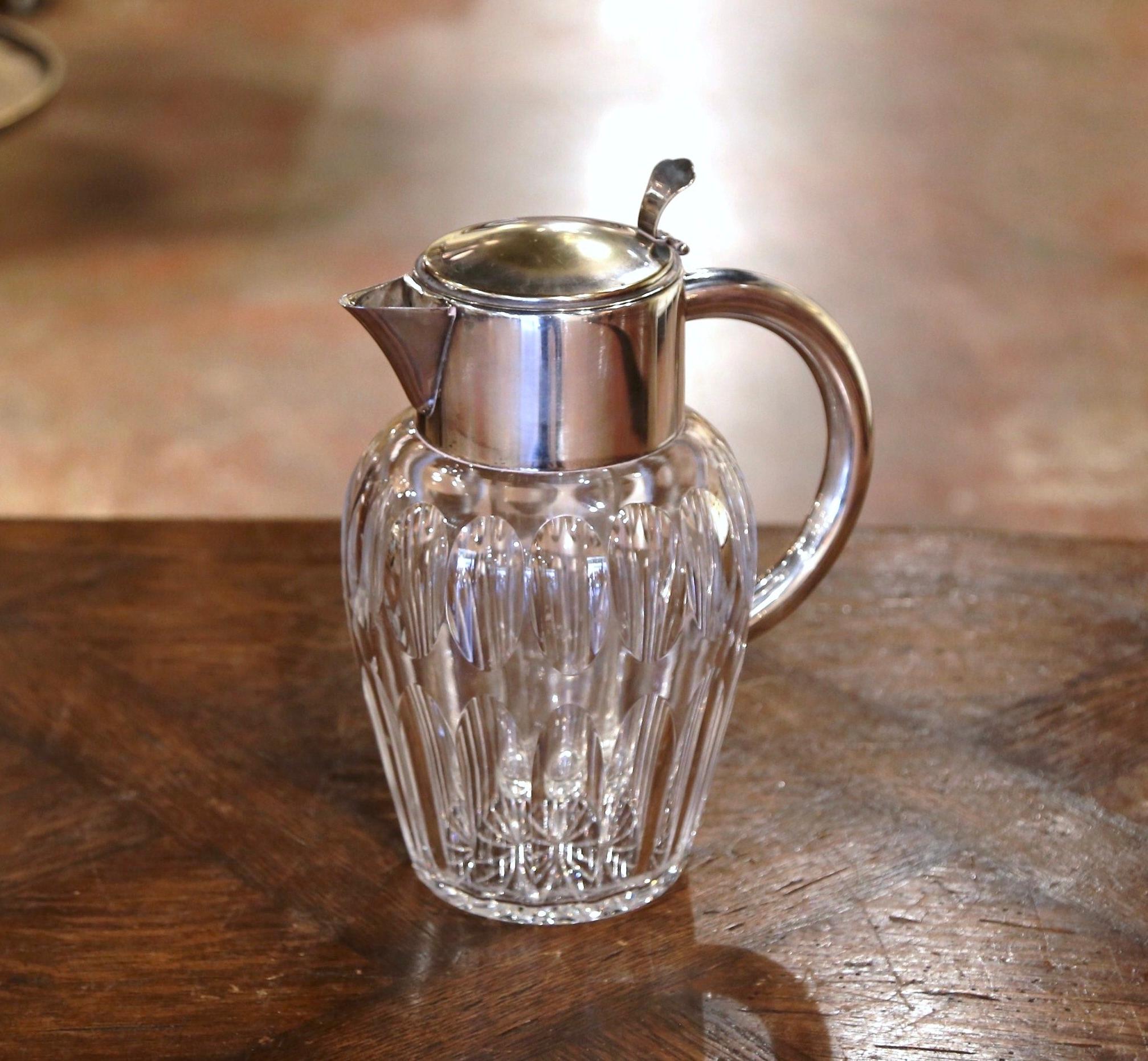 Crafted in France circa 1950, the large pitcher features a round cut glass body and dressed with a silvered brass neck, top and handle. Lifting up the top and removing the CAP, there is an insert ice container in order to keep drinks fresh and cold.