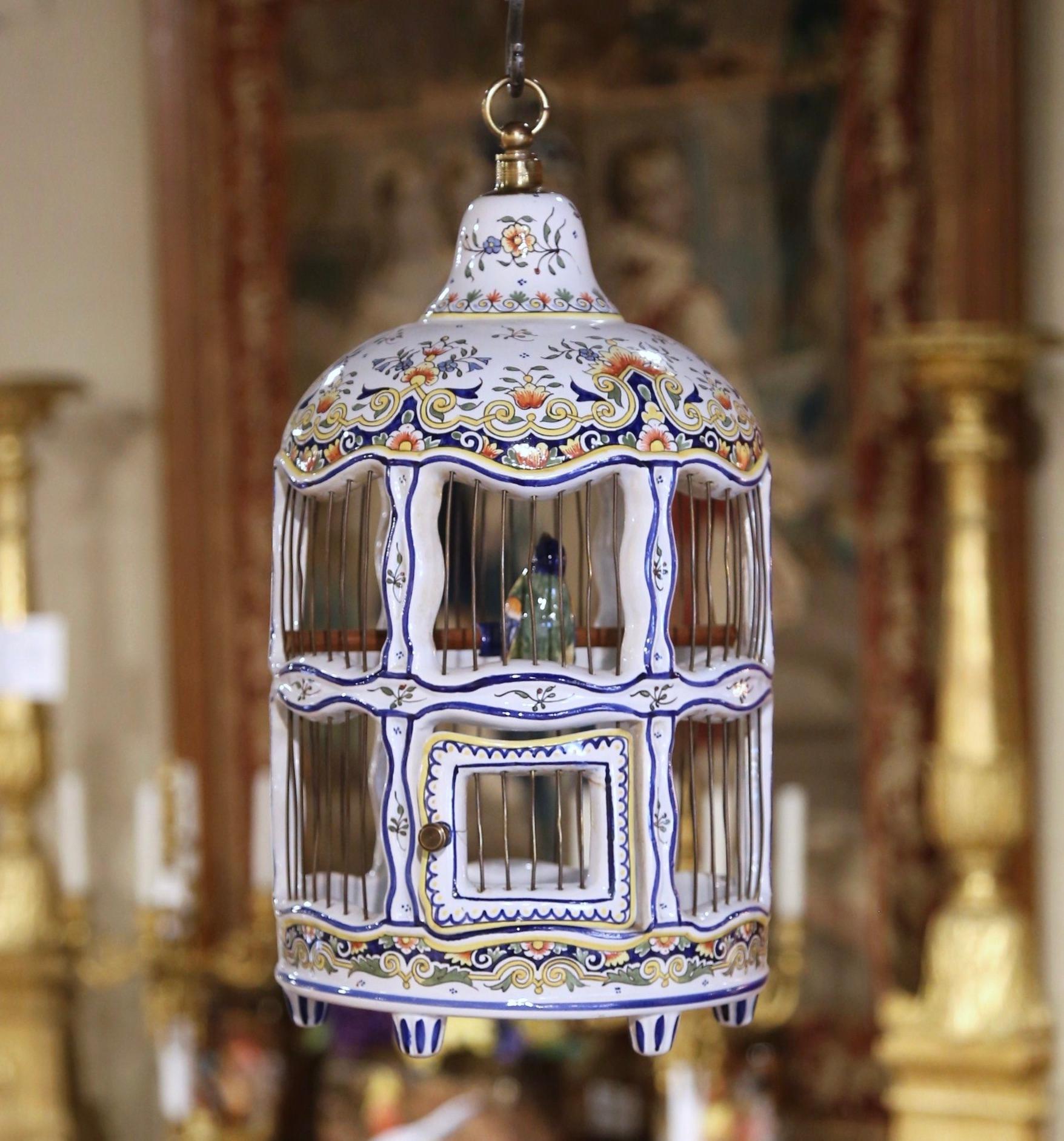 This beautiful, feminine faience birdcage would make a lovely addition to a woman's office or study. Crafted in Rouen, Normandy circa 1960, the cage stands on tapered feet over a straight apron decorated with foliage motifs. The scalloped dome top