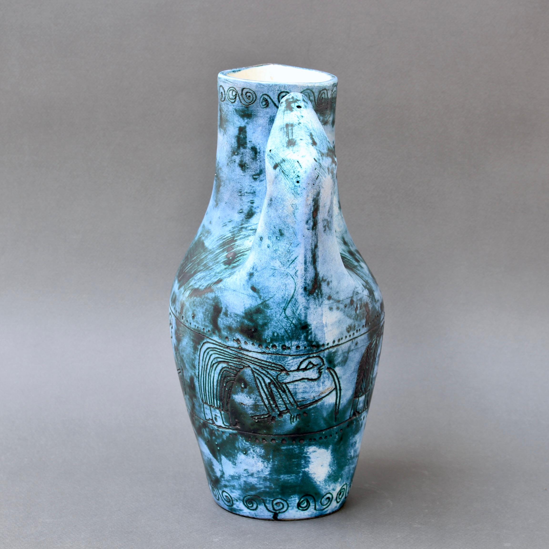 Vintage French ceramic decorative pitcher / decanter / vase (circa 1950s) by Jacques Blin. The vase is in a subtle blue hue covered in Blin's trademark misty glaze. It is decorated with a frieze of crouching figures planting the fields supported