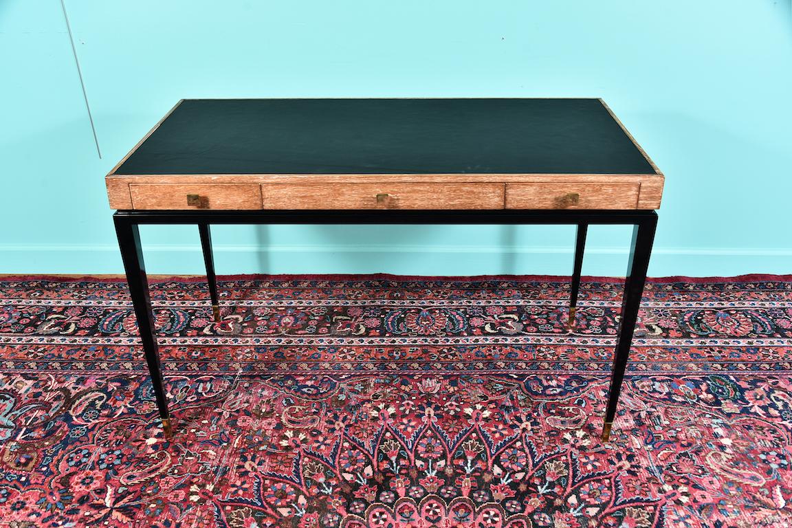 Midcentury French desk in white oakwood

Desk is made out of white oakwood. It has its natural look all the way at the edges of the desk top and legs are made out of ebonized oakwood.
Bottoms of legs have brass tips. Desk top is covered with