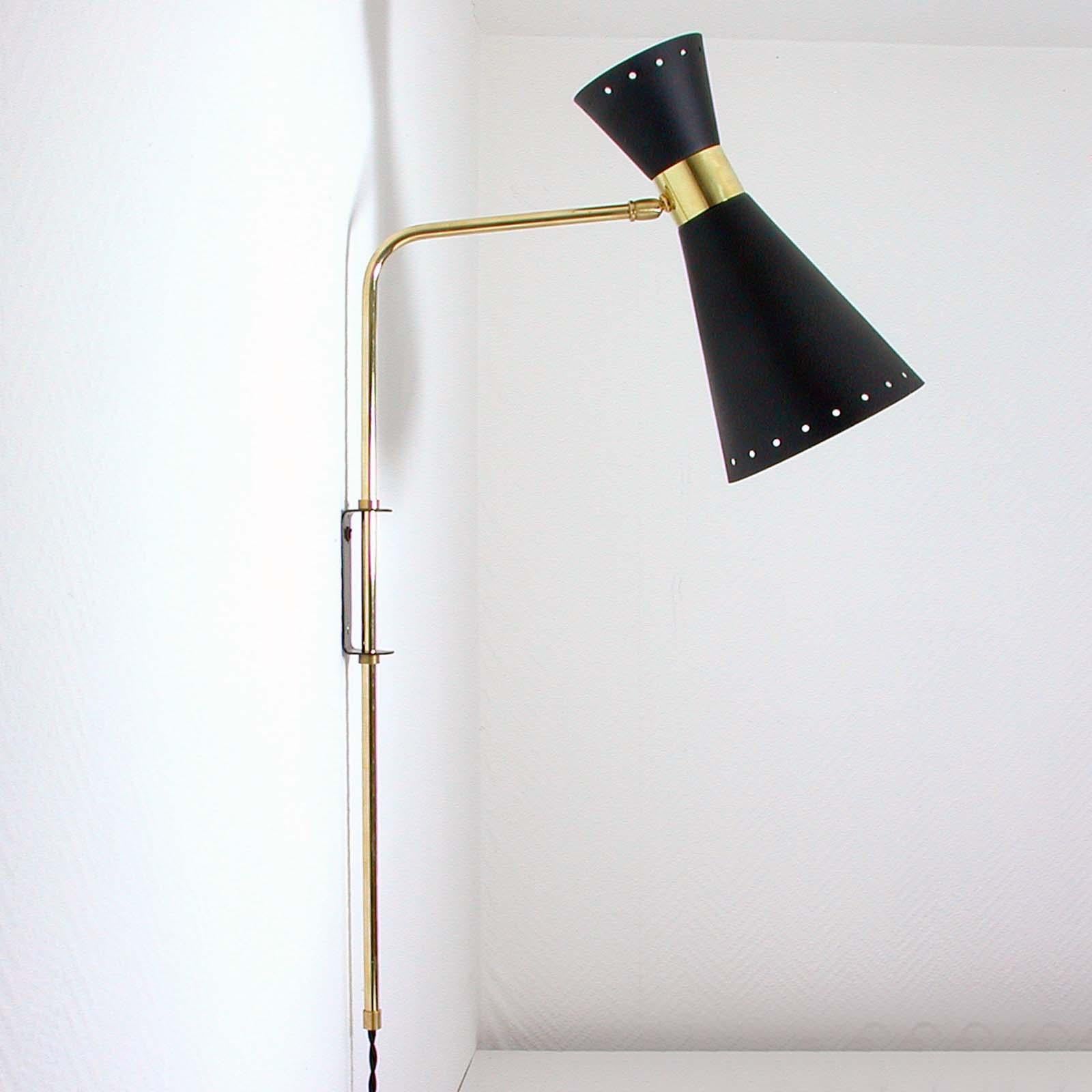 This awesome articulating wall lamp with adjustable shade and height adjustable lamp arm was made in France in the 1950s. The light features a lampshade made of black lacquered metal with brass details. The swiveling and adjustable lamp arm is made