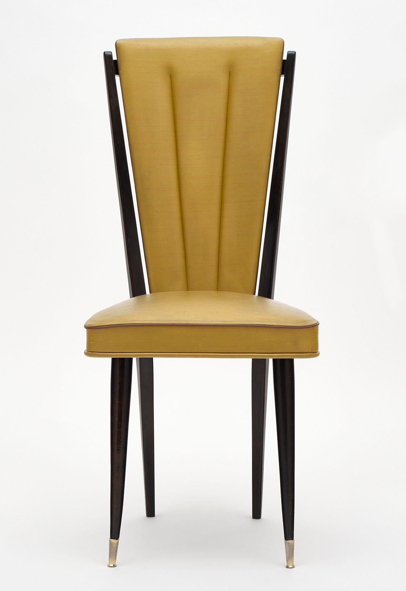 Set of five mid-century French dining chairs made of beech wood. They feature the original vinyl upholstery and tapered legs with brass feet.